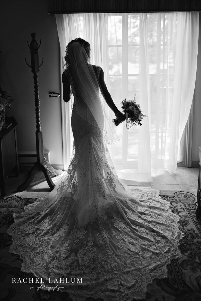 Black and white silhouette of a bride looking out the window as she gets for her wedding day at Panola Valley Gardens.