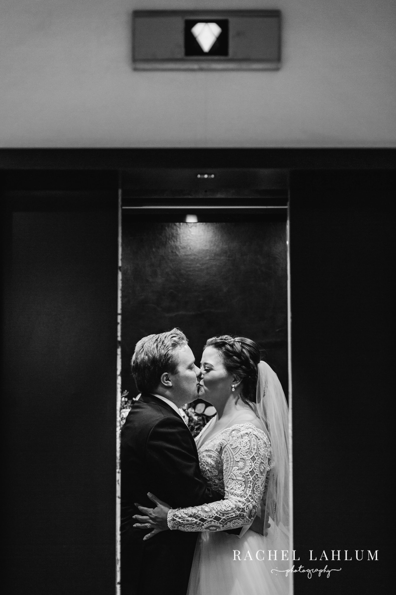 Black and white portrait of bride and groom sharing a kiss before wedding ceremony. 