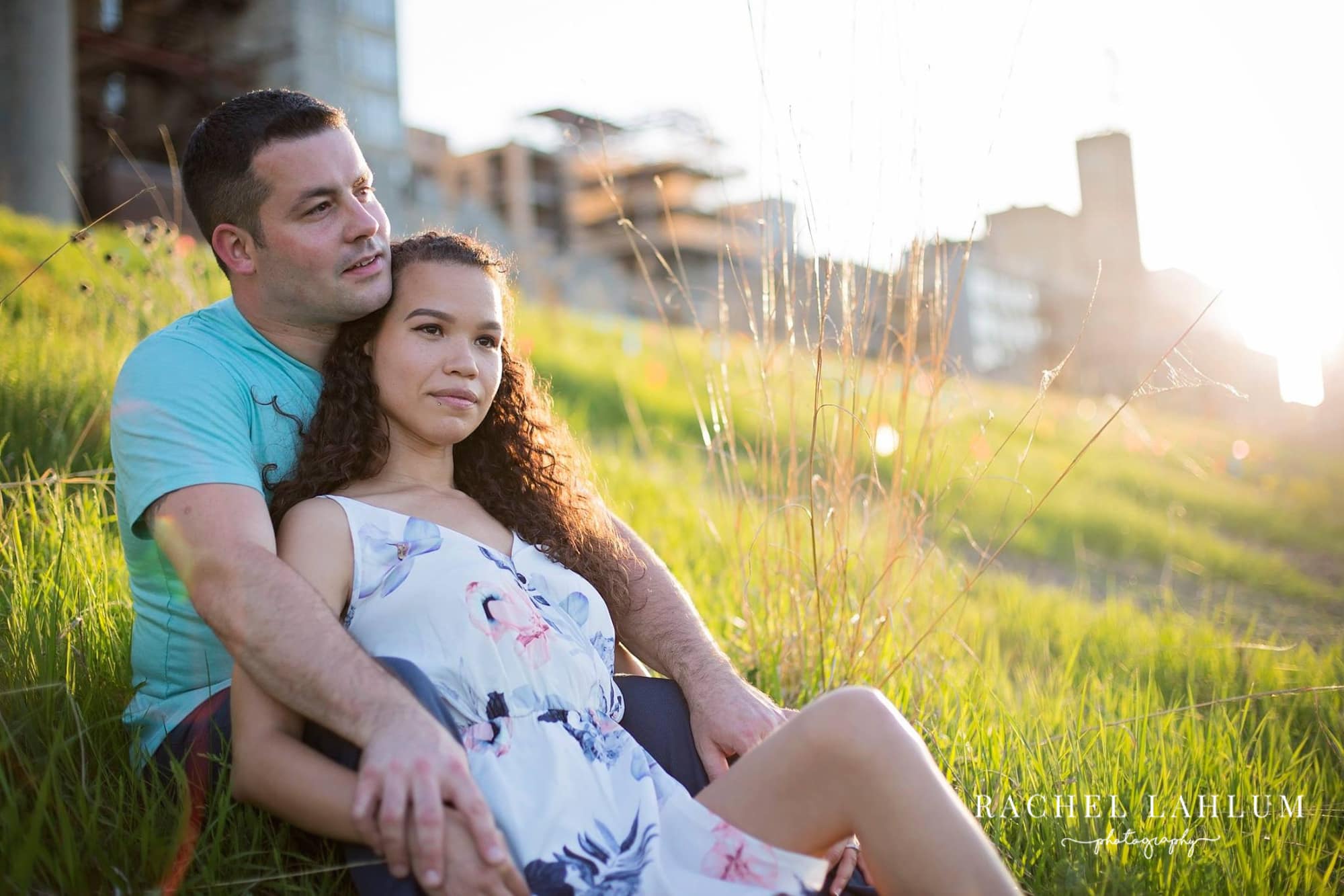Couple sits in a grassy field for engagement session in Downtown Minneapolis.