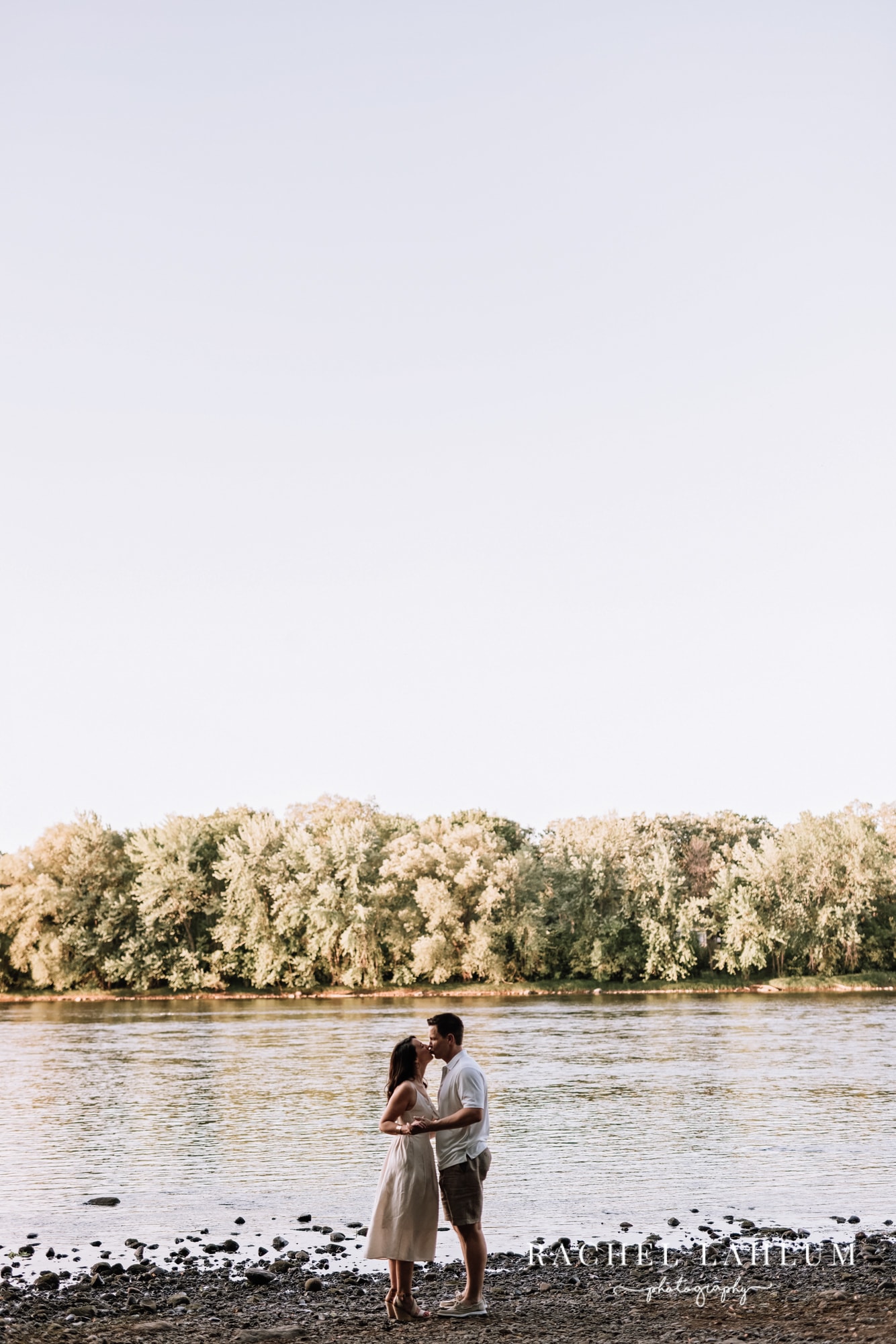 Couple kiss by the river during engagement photography session. 