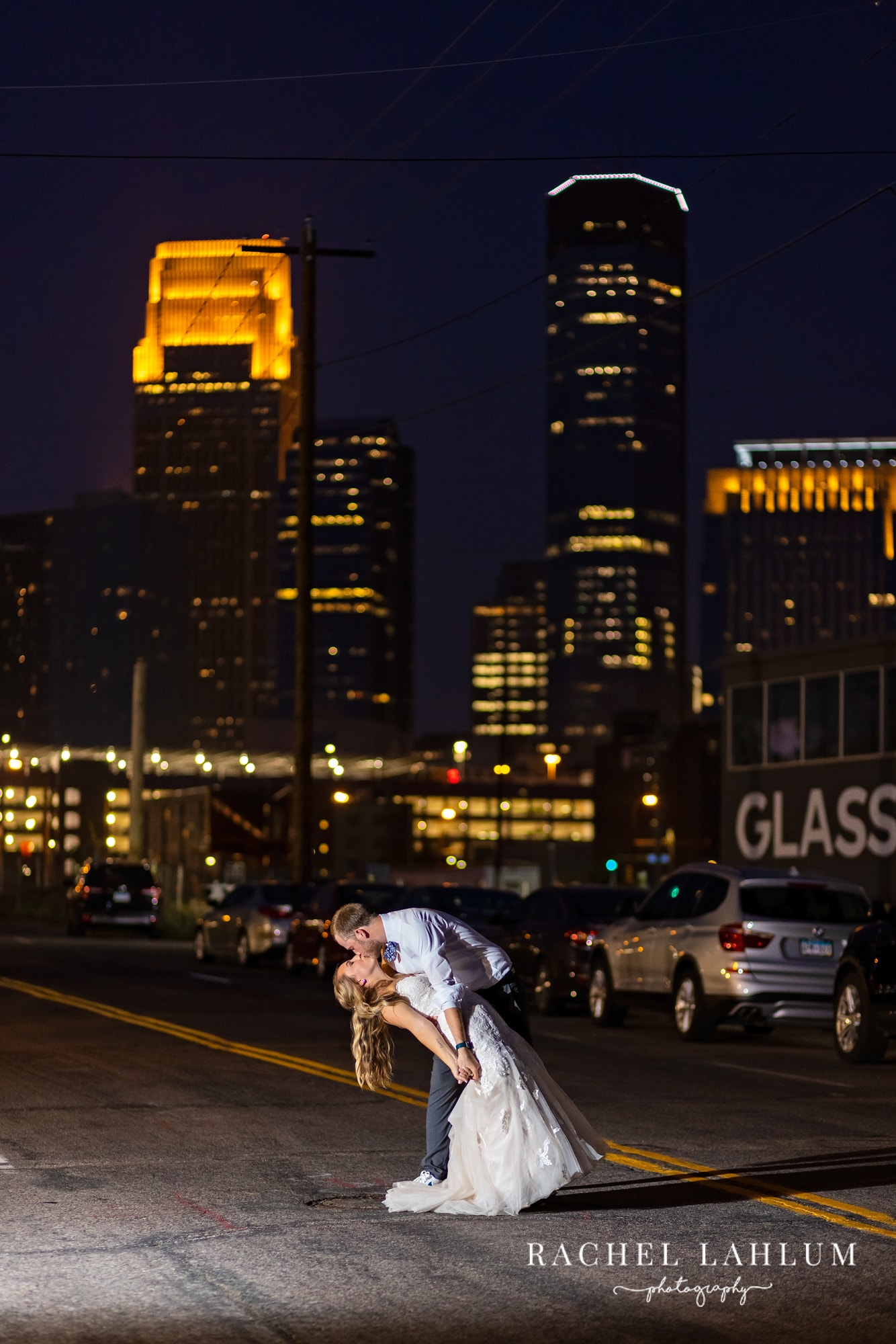 Groom dips bride in front of the Minneapolis Skyline at night after wedding at The Holden Room. 
