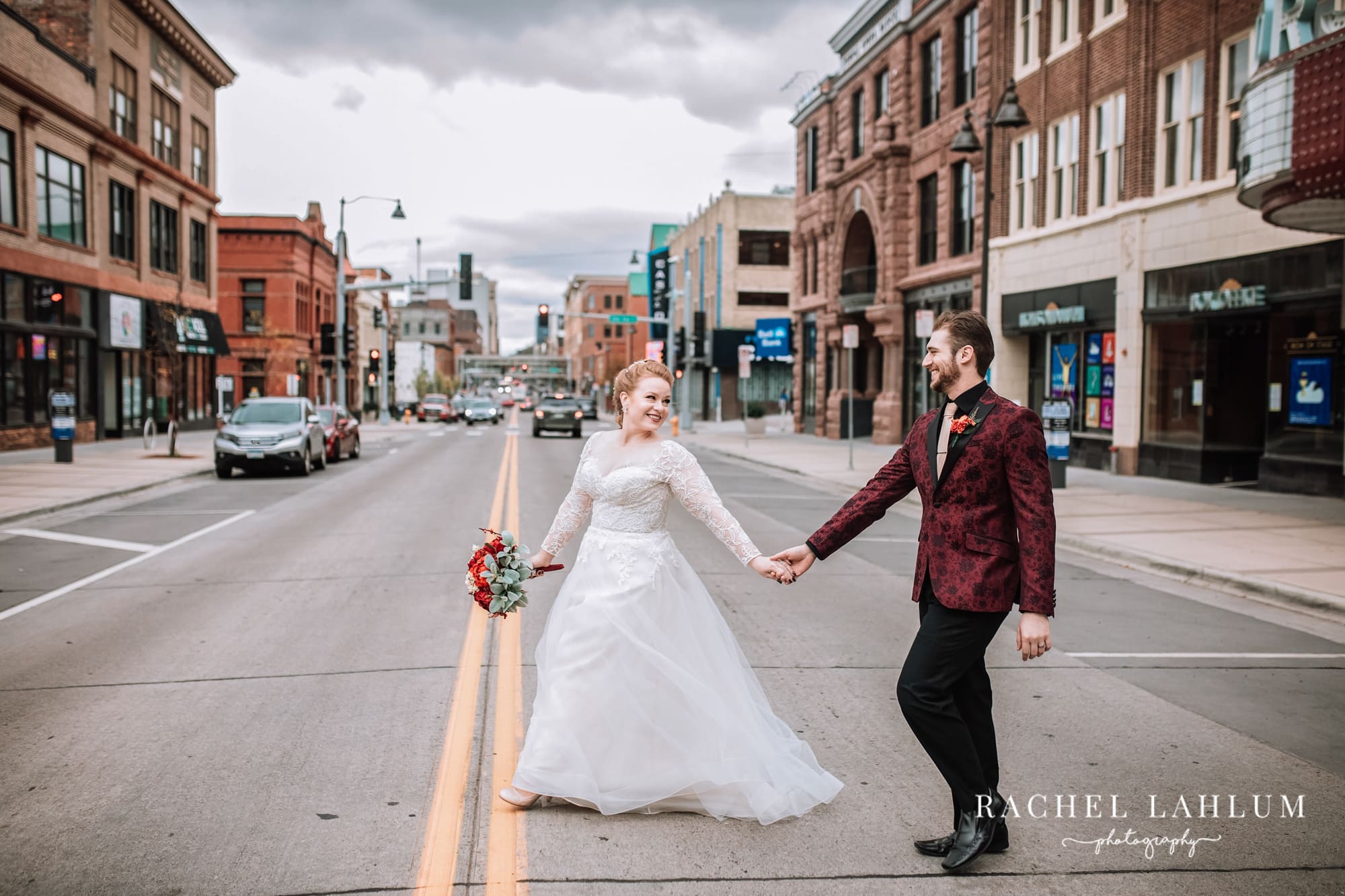 Bride looks back at groom as they cross a street in Duluth, Minnesota.