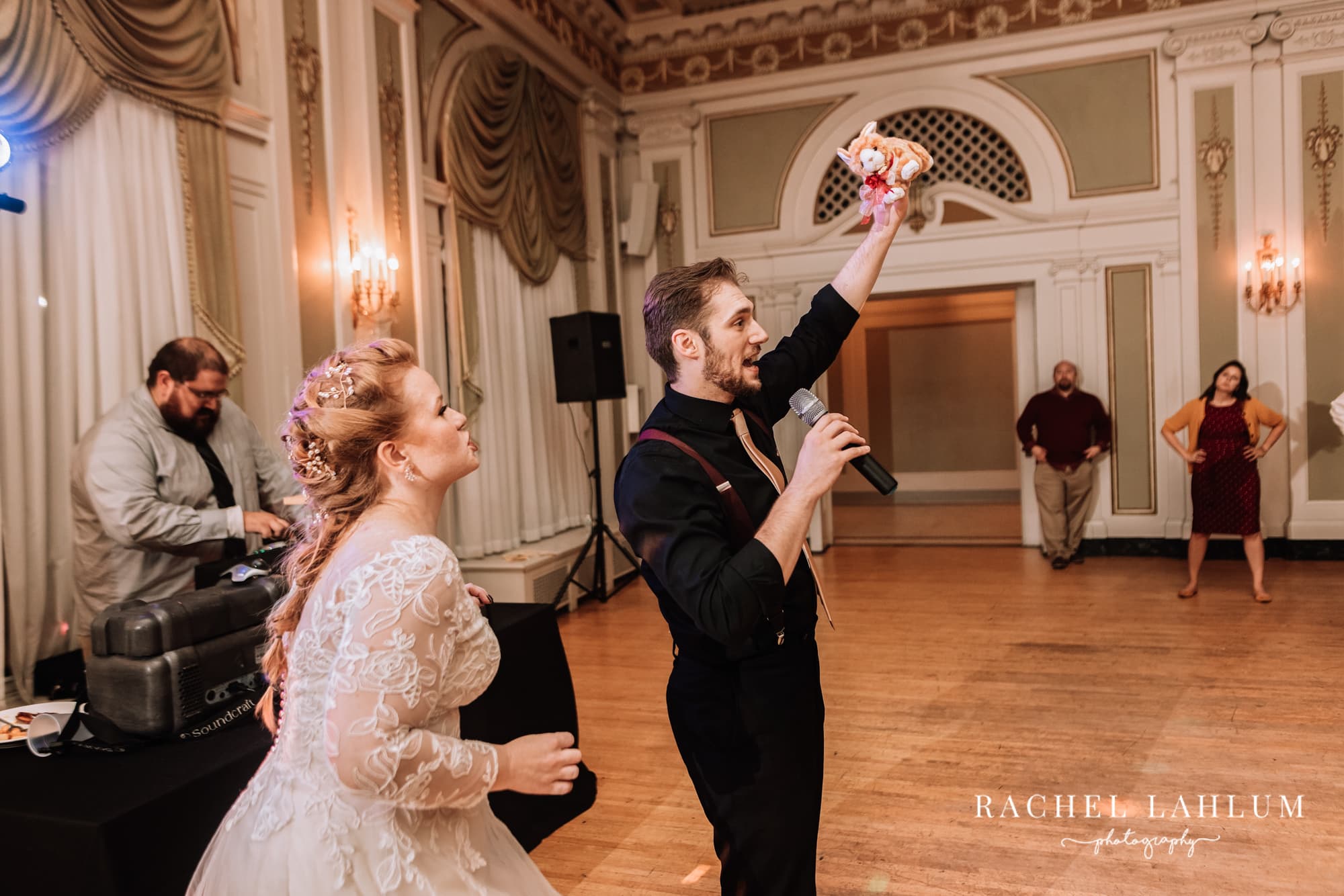 Groom holds up stuffed animal to be thrown into the audience in place of a wedding bouquet.