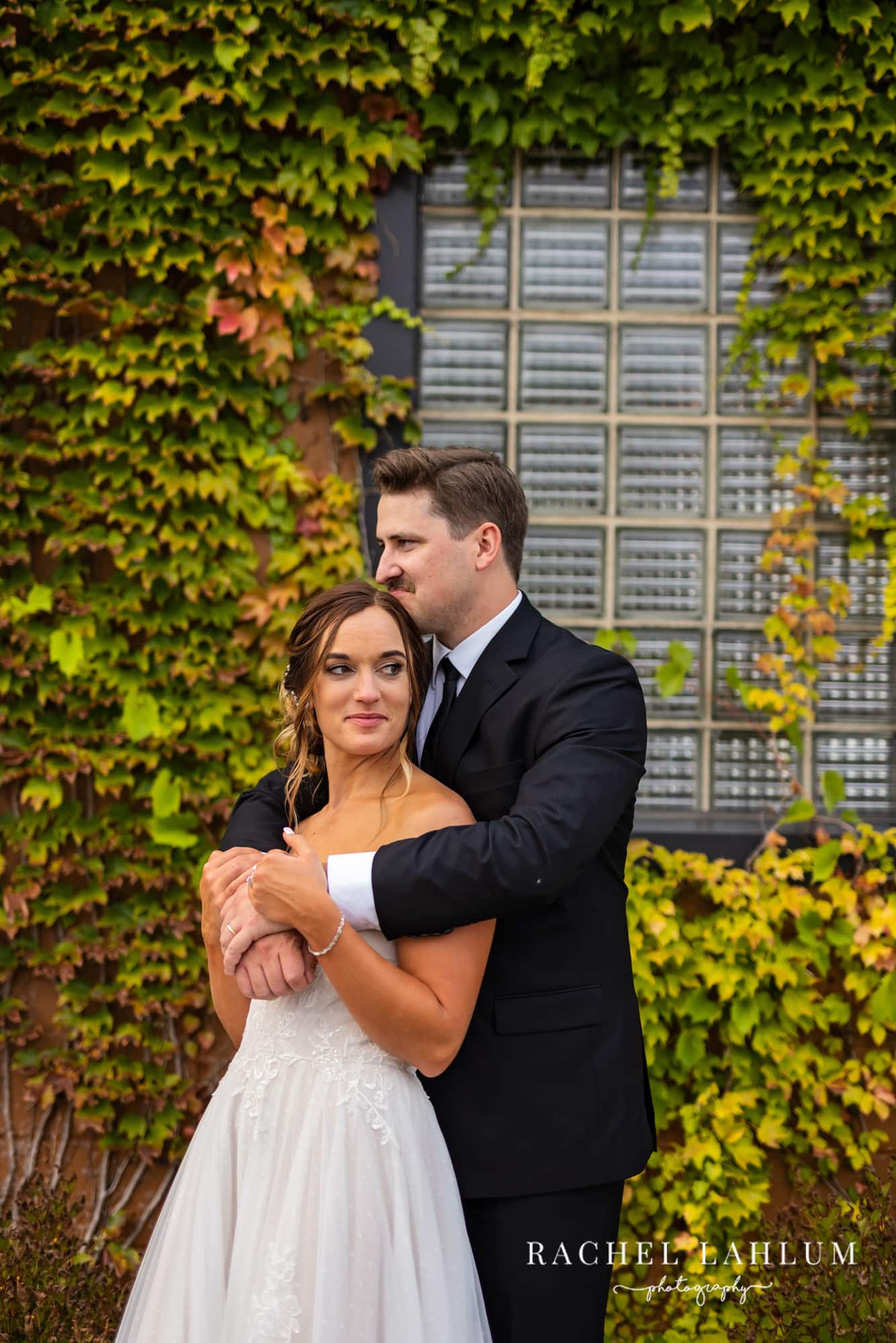 Bride and groom pose for wedding photography in front of an ivy wall at The Boathouse in Alexanrdia, Minnesota.