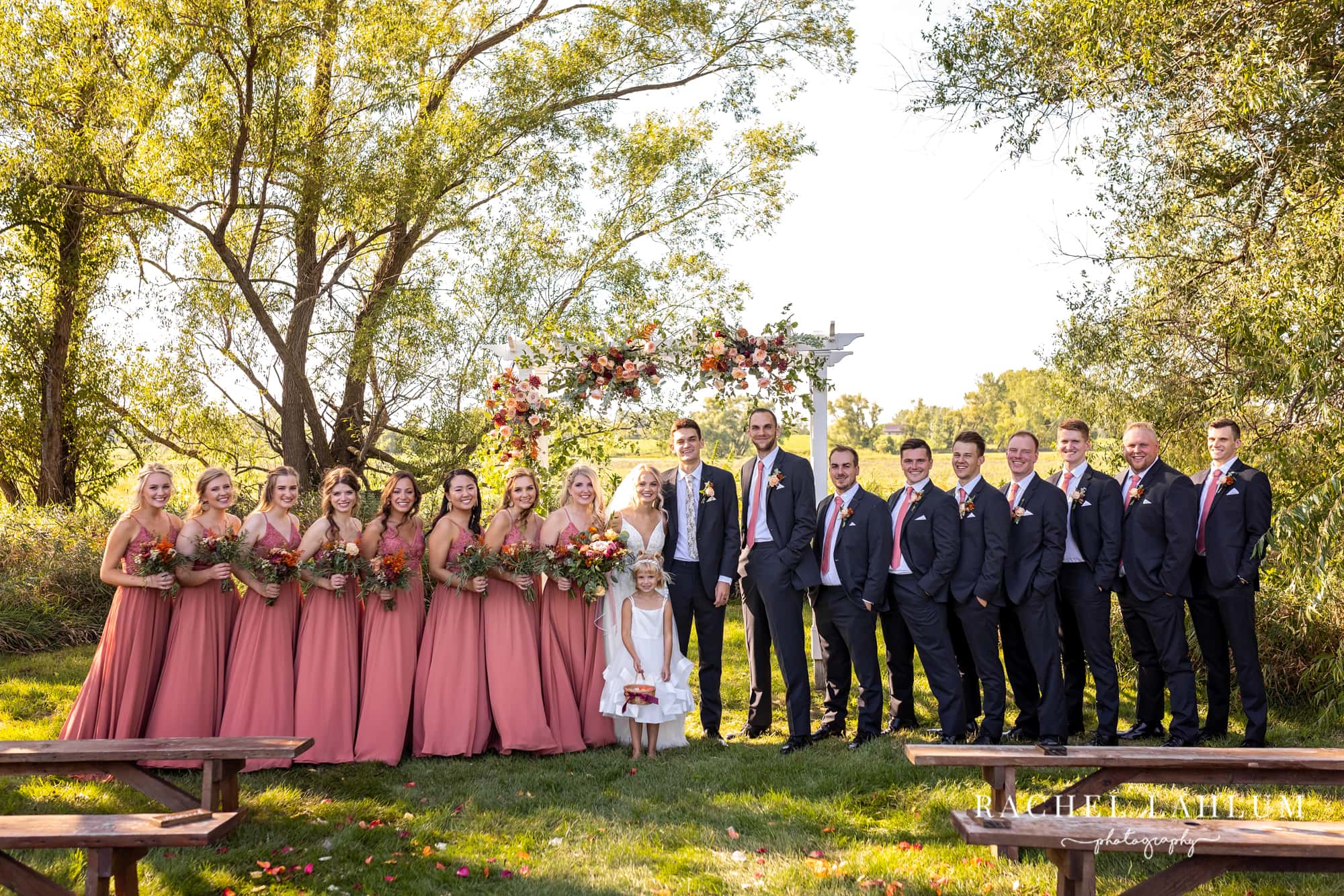 Bride and groom pose with wedding party after outdoor ceremony at The Cottage Farmhouse. 
