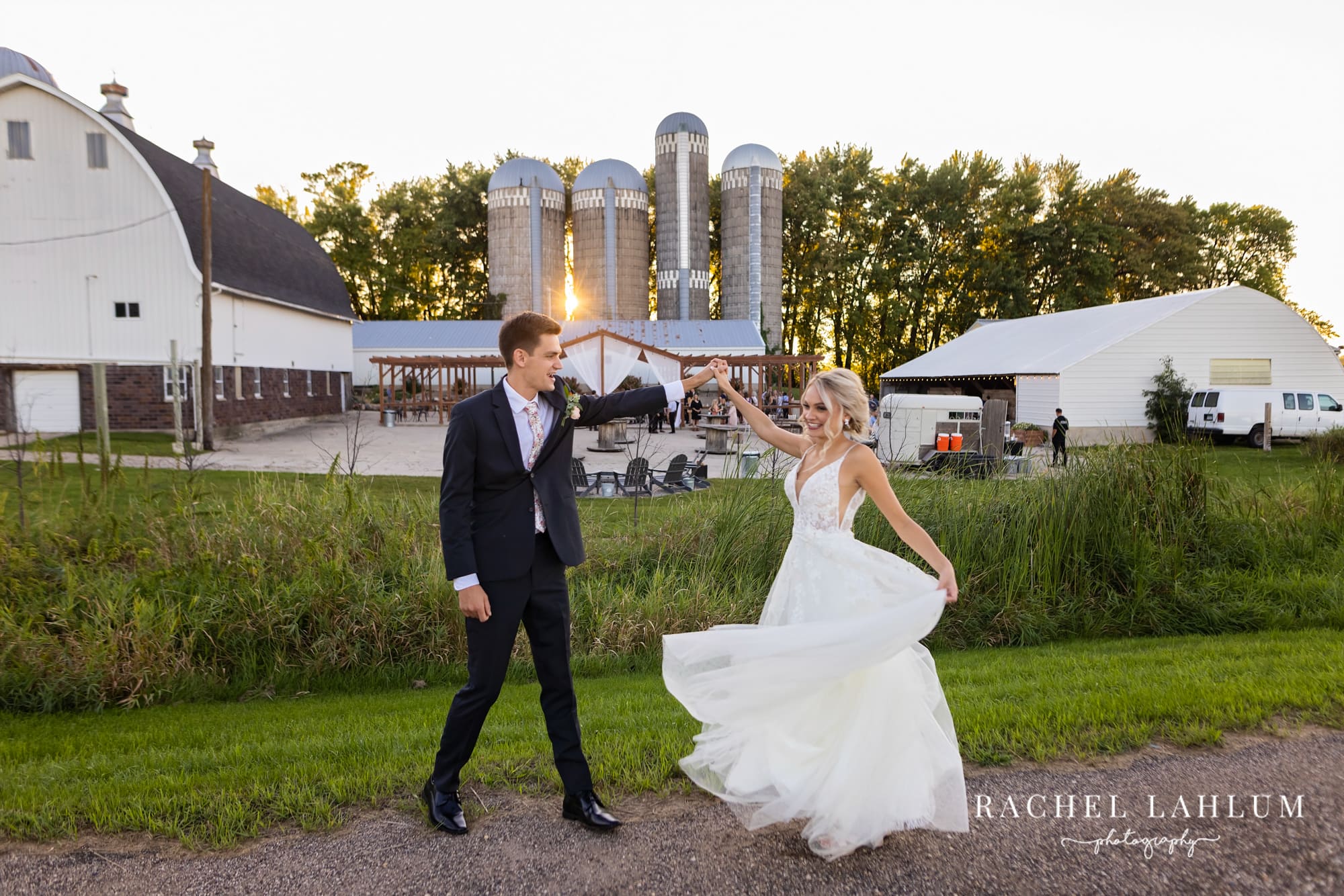 Groom twirls bride in front of the Cottage Farmhouse in Glencoe, Minnesota.