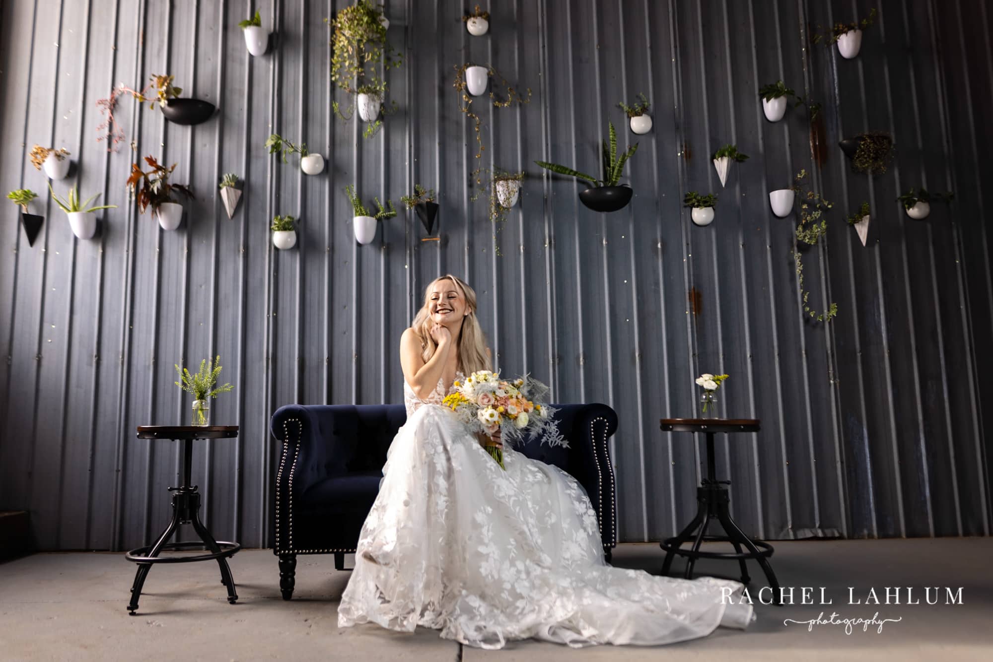 Bride poses in front of aluminum wall with wedding decorations at The Sinclair on Grand. 