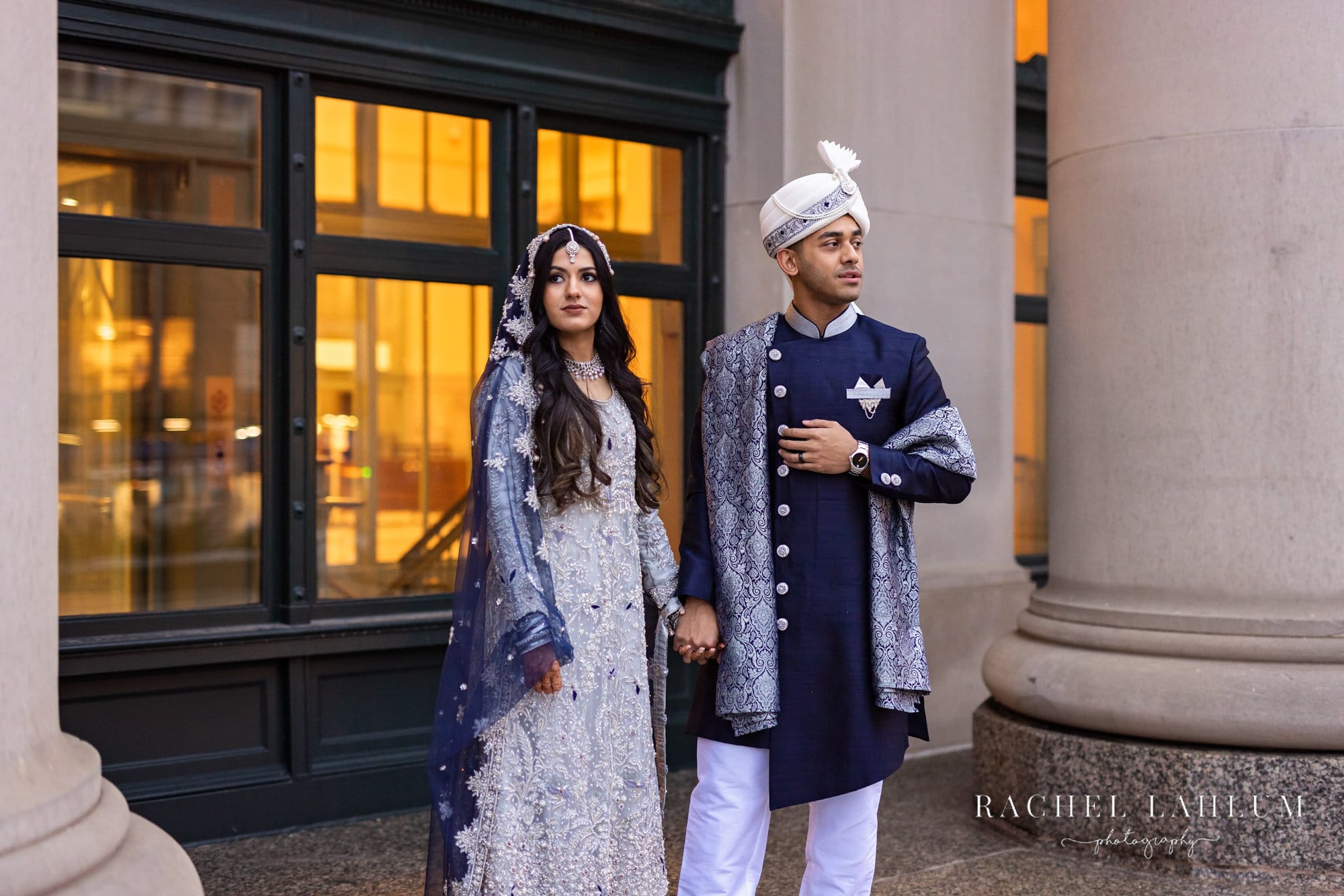 Couple in ceremonial South Asian wedding attire stands in front of St. Paul Union Depot.