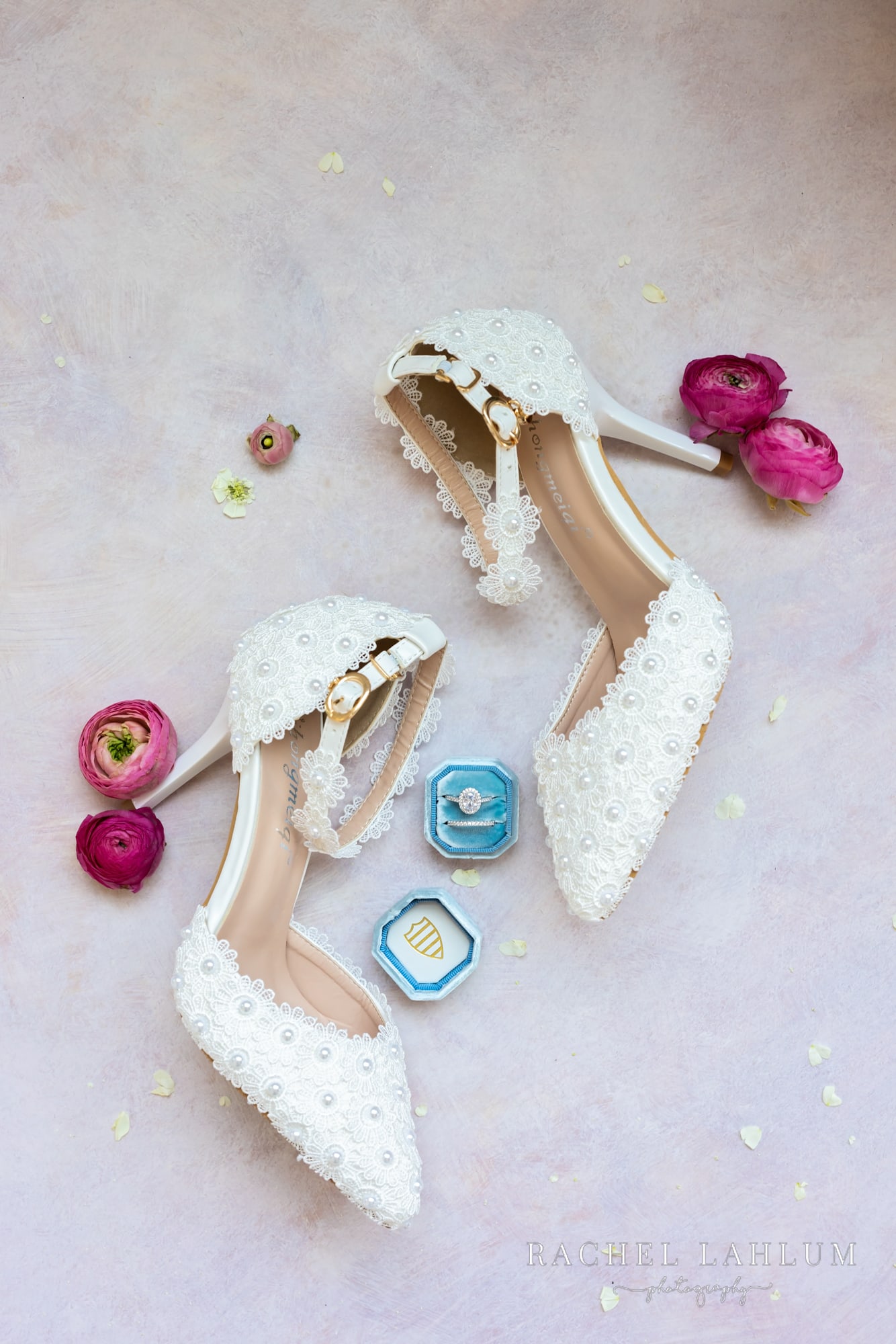 Bride’s high-heel shoes lie sideways with wedding ring in between.