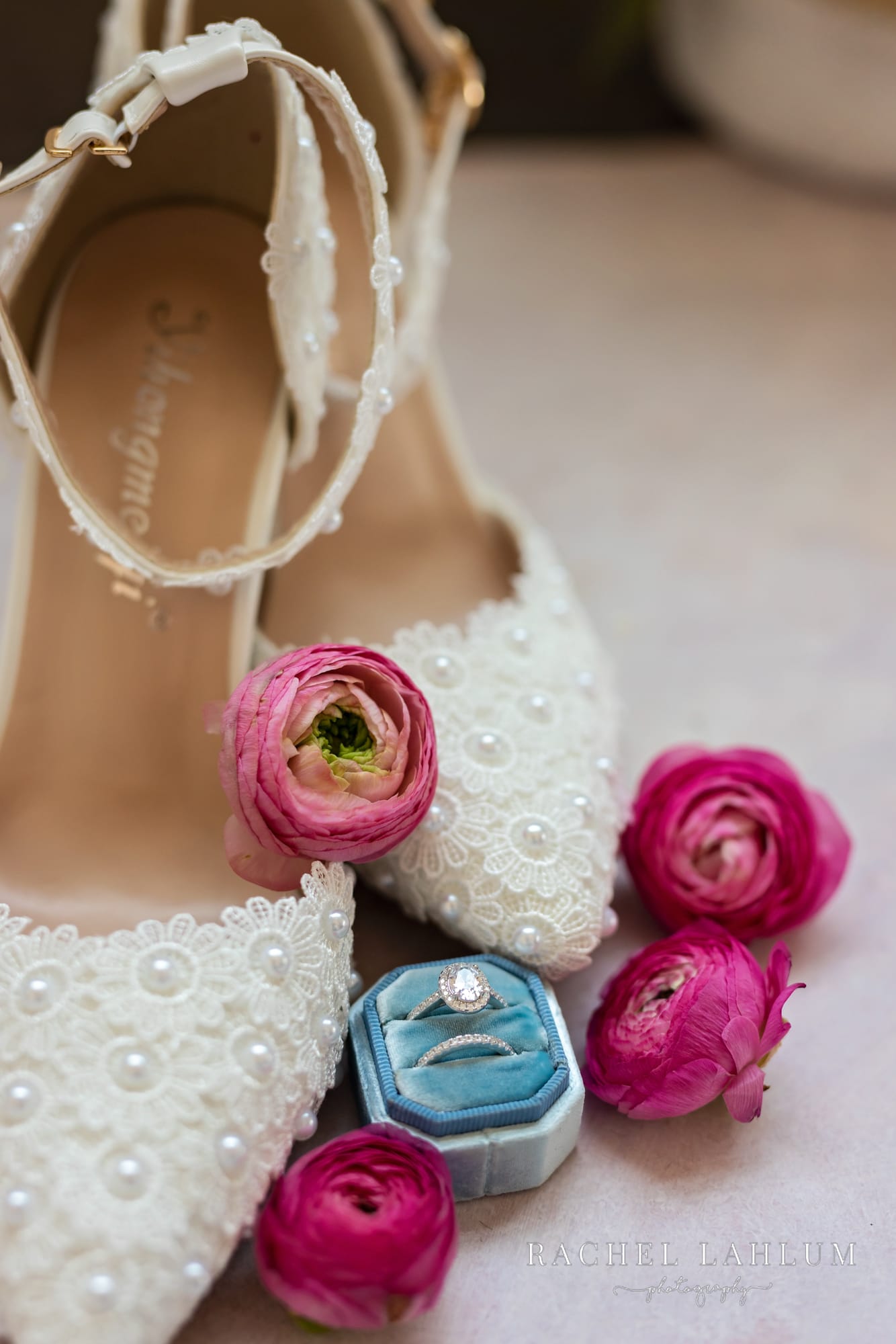 Close-up photo of wedding ring in box with pink flowers and details of wedding shoes.