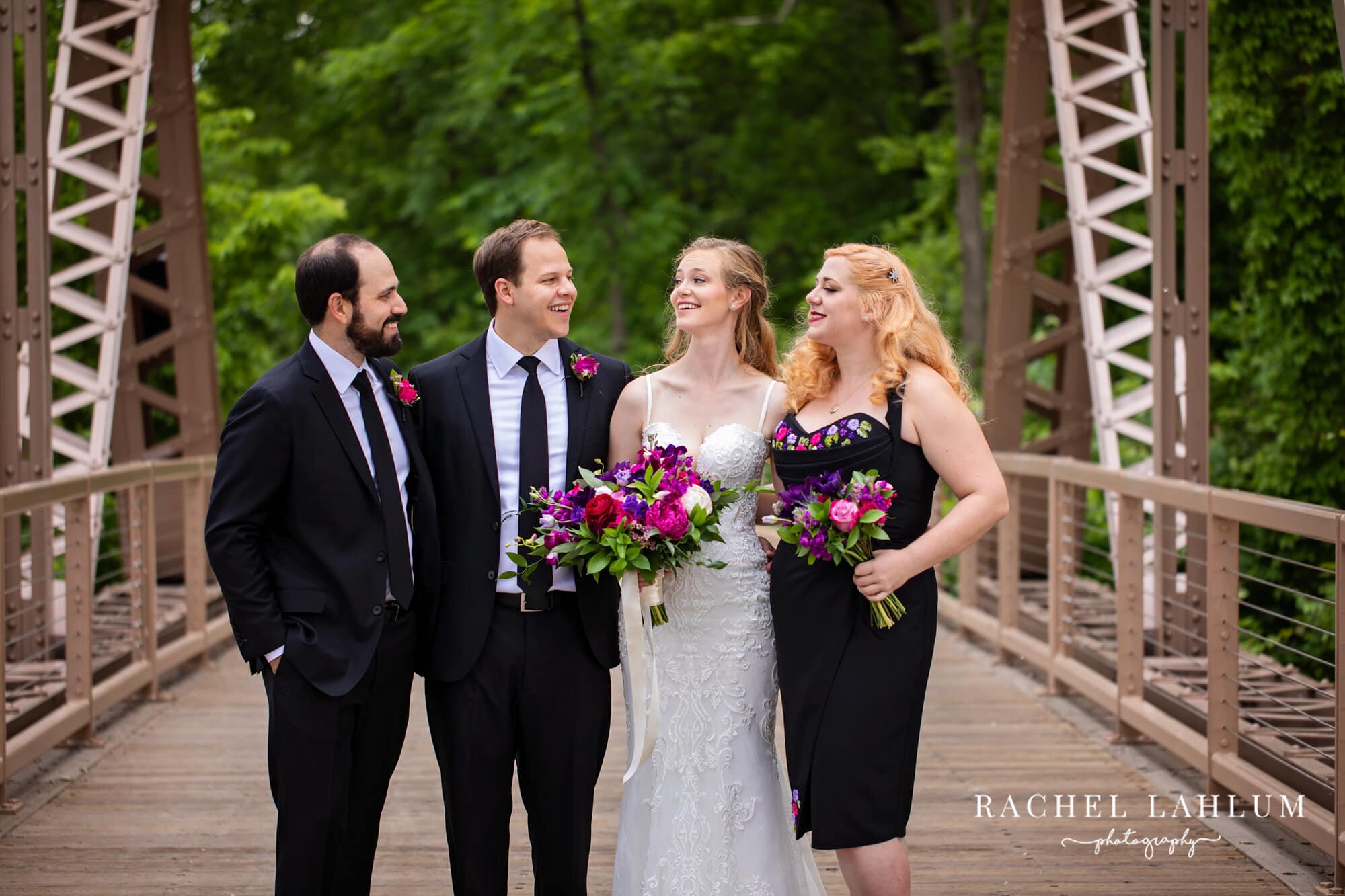 Best man, groom, bride, and maid of honor pose for a wedding portrait on a bridge. 