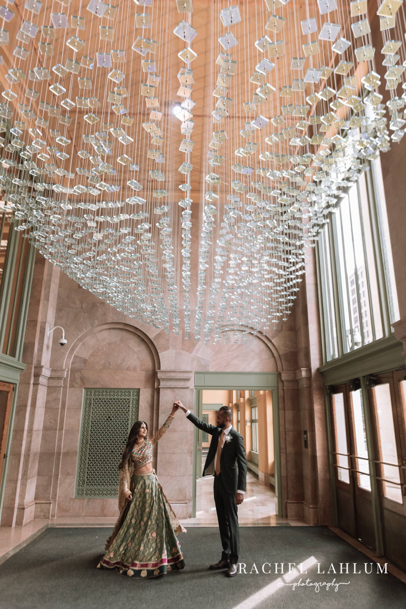 Groom twirls bride under glass ceiling decorations at the Intercontinental in St. Paul, MN.