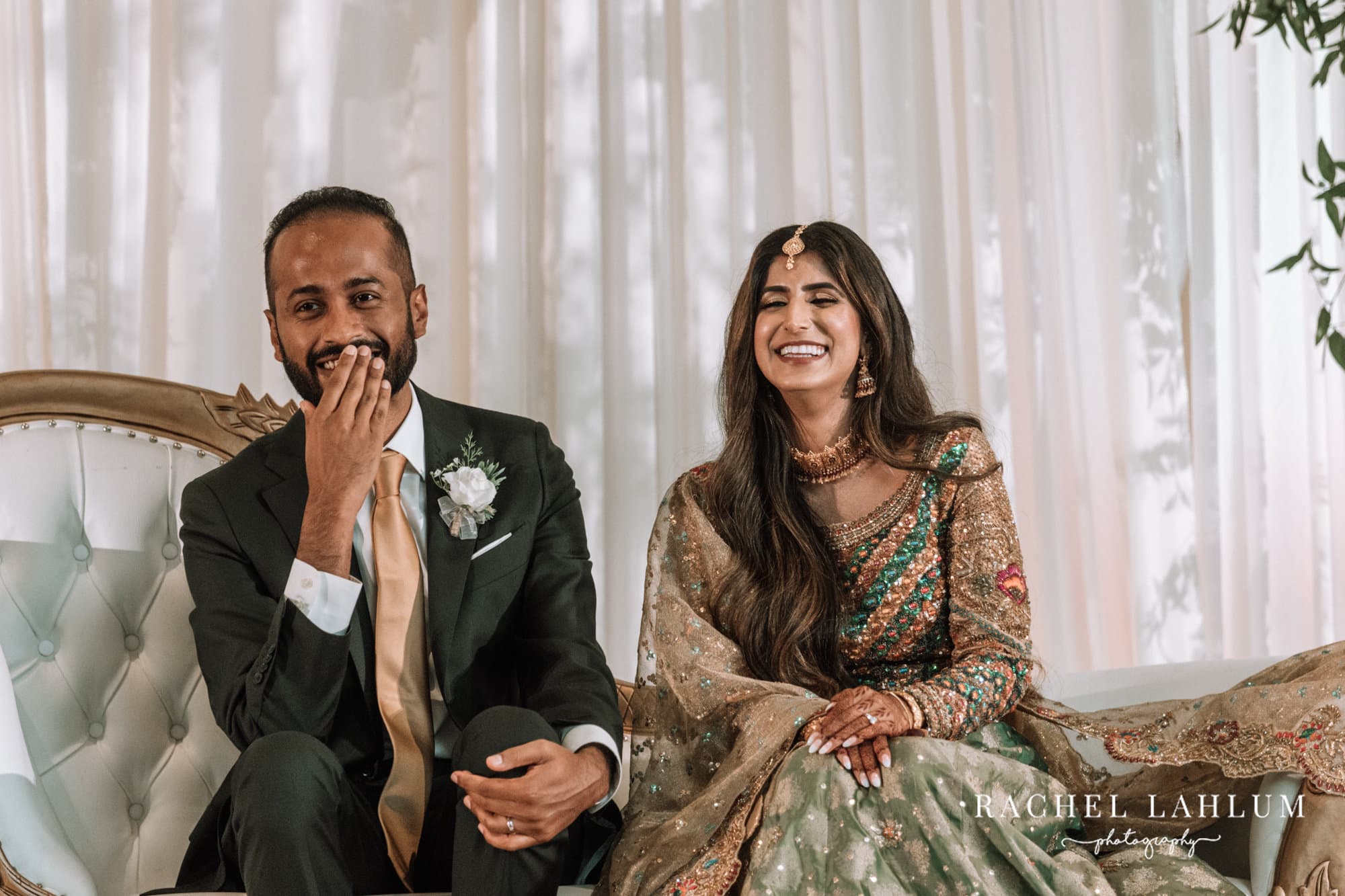 Bride and groom laugh during speeches at Walima celebration.