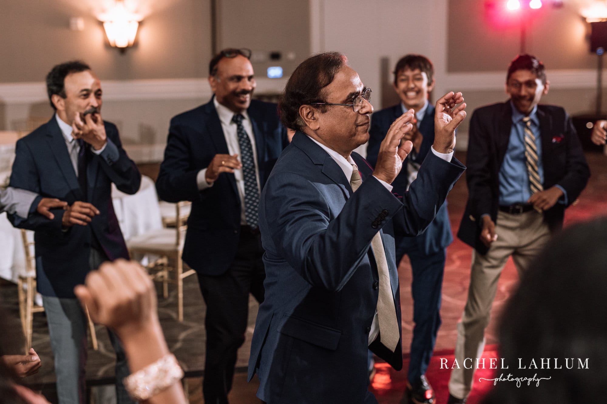 Wedding guests surround the grooms father as he dances. 