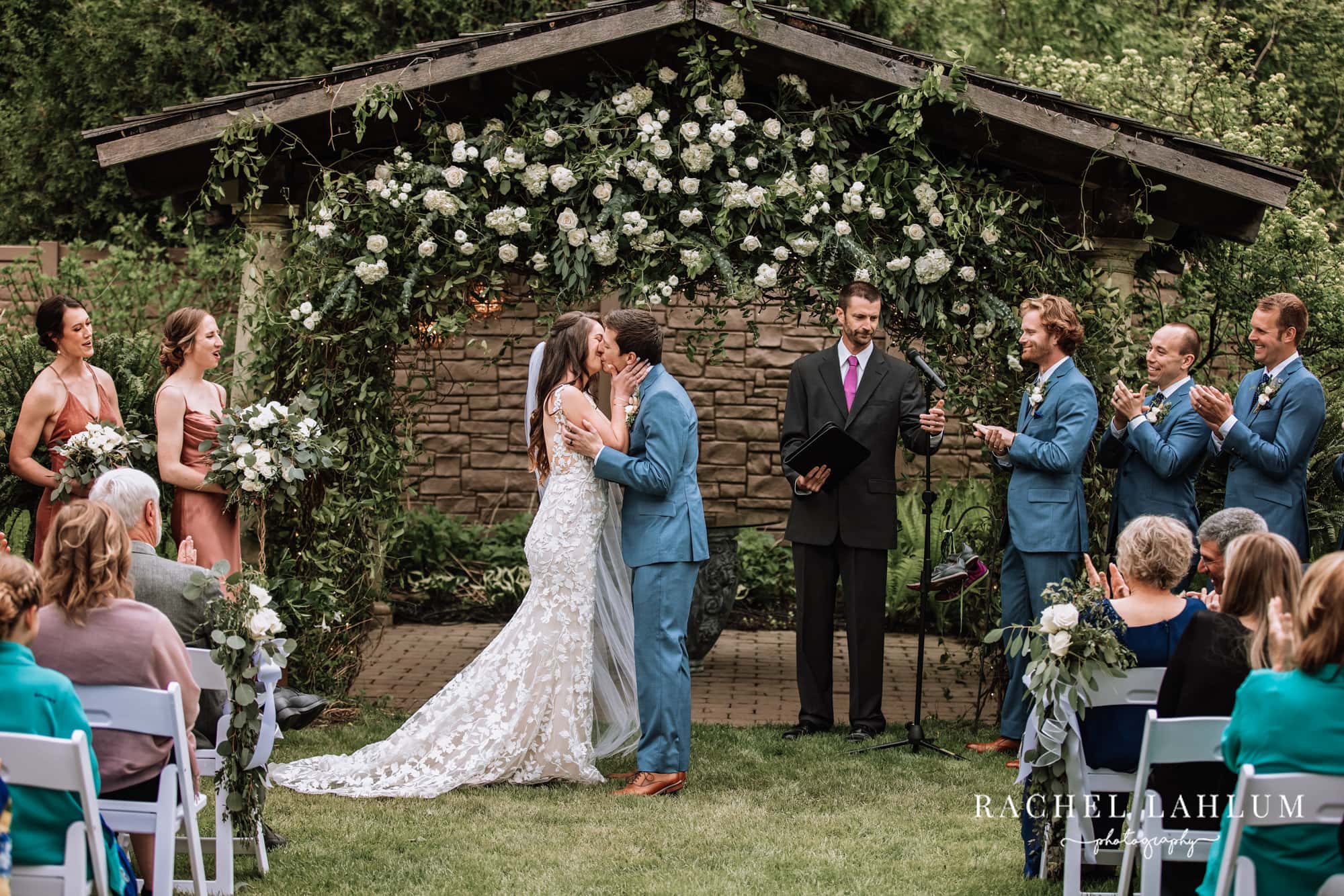 Newlyweds kiss under a floral archway at Camrose Hill Flower Farm in Stillwater, Minnesota.