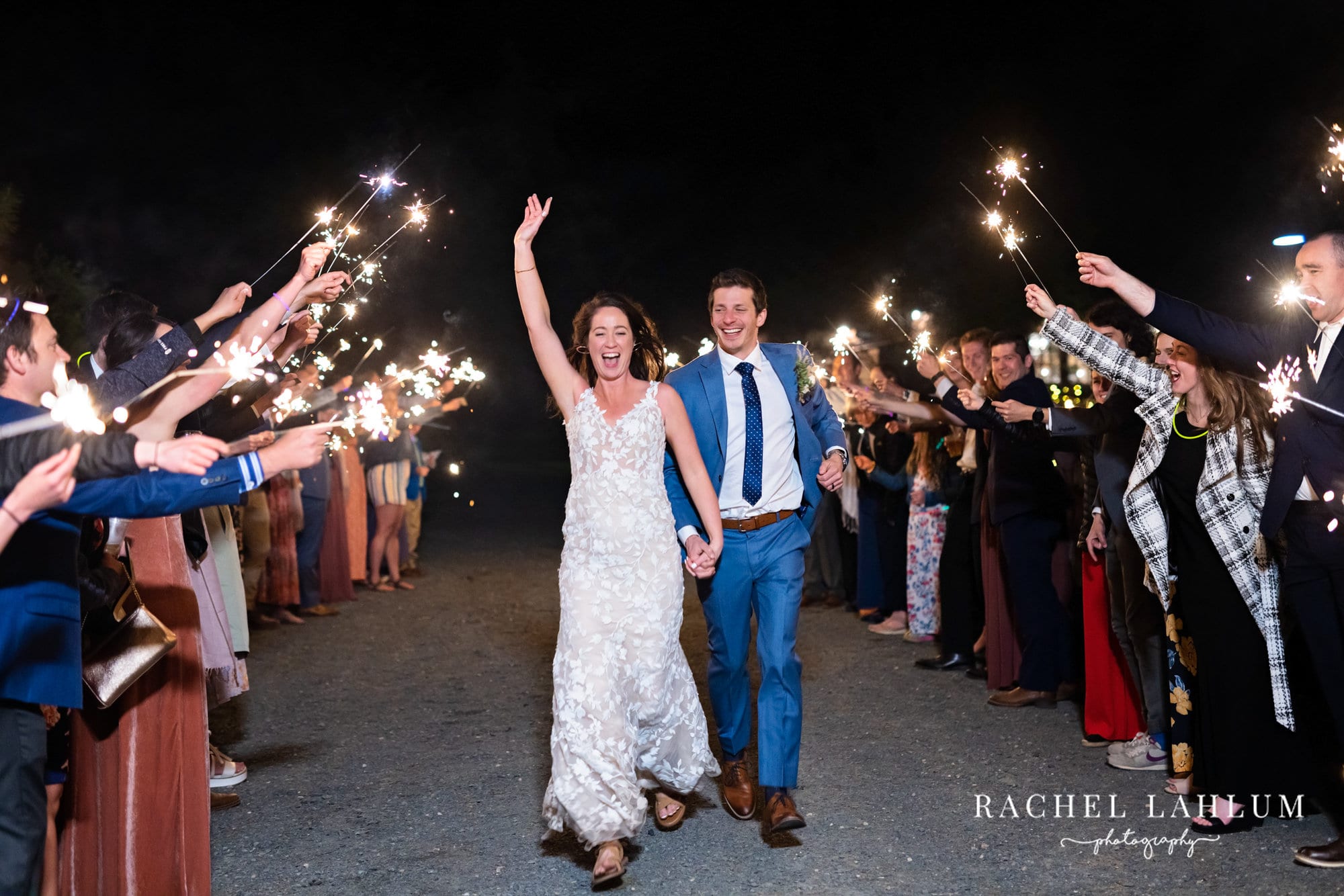 Newlyweds run through a sparkler tunnel after wedding and reception at Camrose Hill Flower Farm in Stillwater, Minnesota.