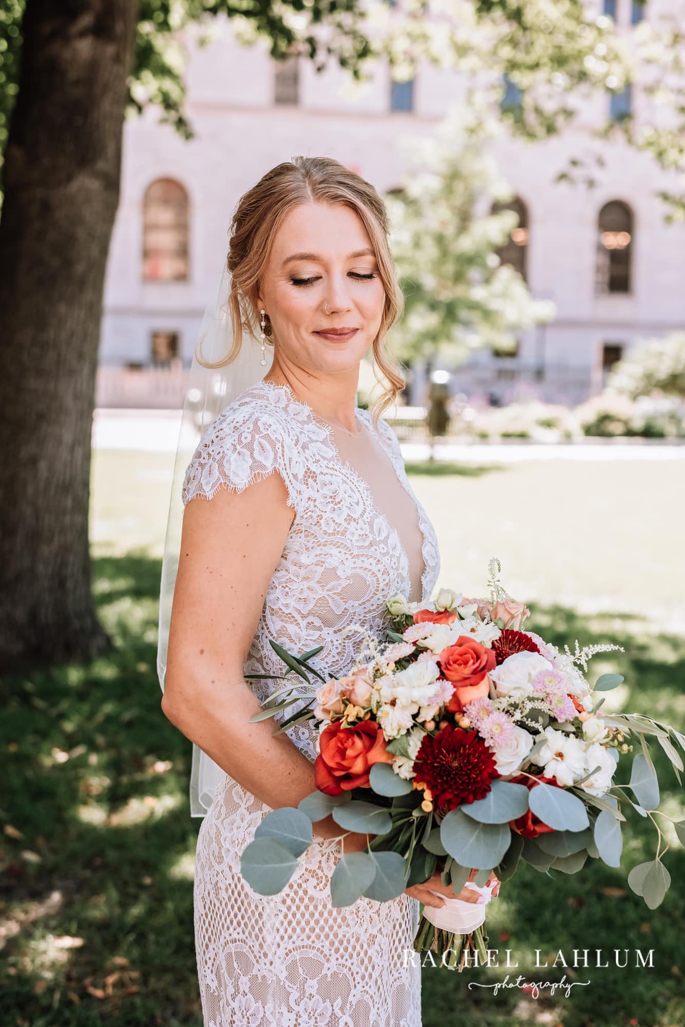 Bride poses with bouquet in front of Harriet Island Pavilion. 