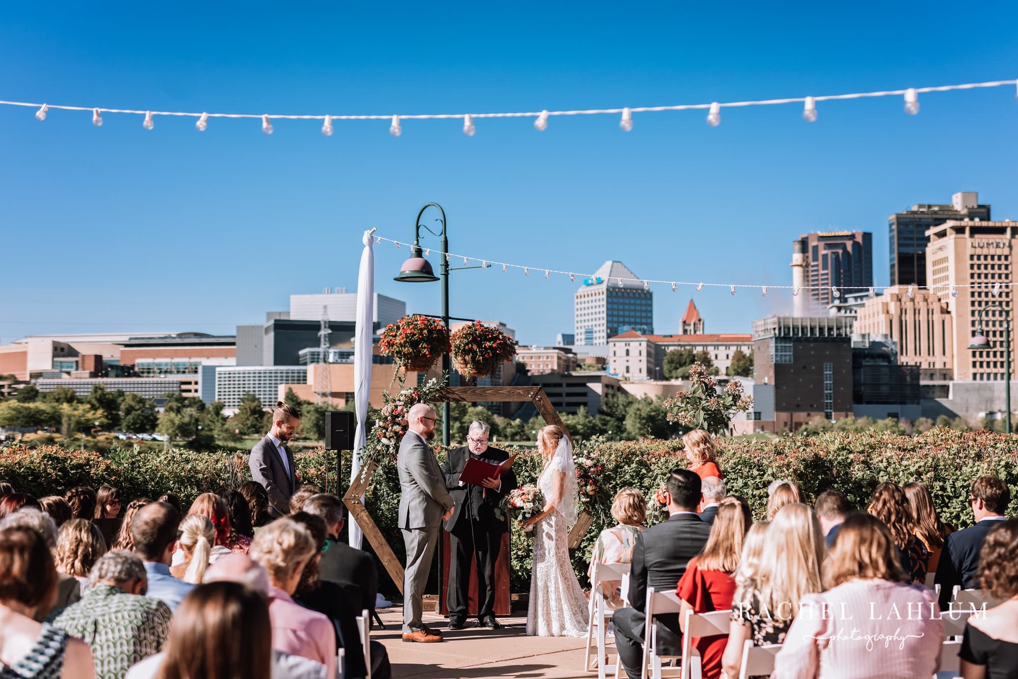 Wedding ceremony for Michelle and Andrew with the St. Paul skyline in background at Harriet Island Pavilion. 
