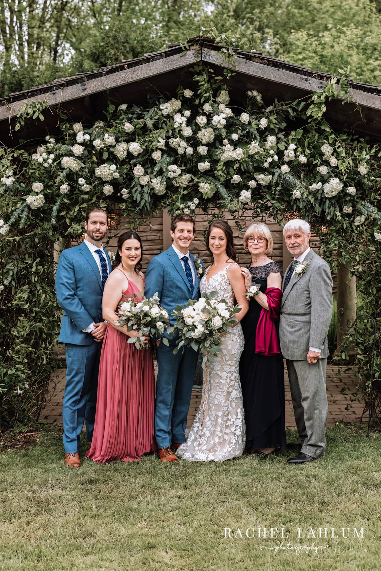Bride and groom pose for a portrait with family under a floral archway at Camrose Hill Flower Farm. 
