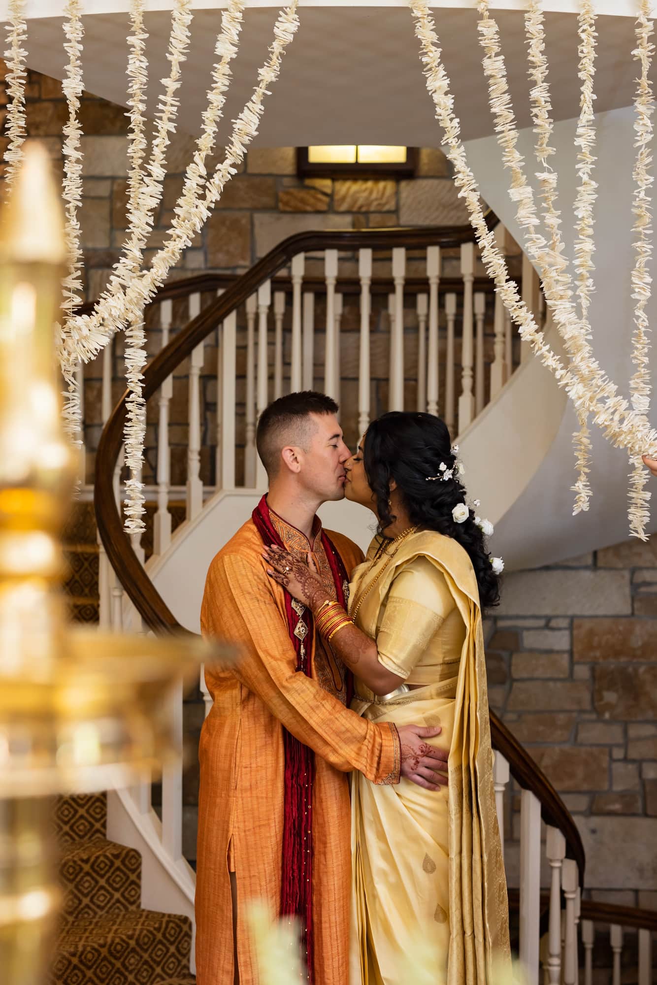 Bride and groom kiss beneath their decorations for their Indian wedding photography at Glenn Oaks Country Club in Des Moines, IA.