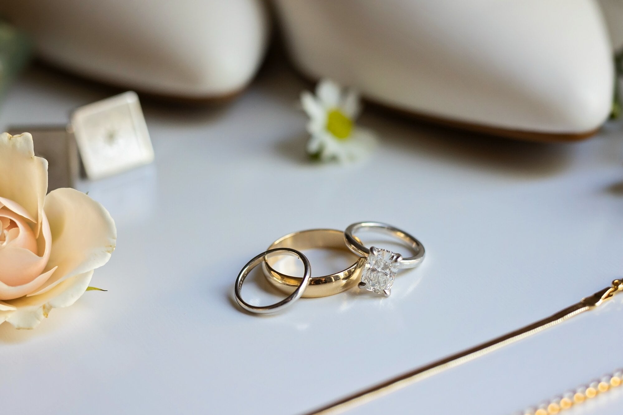 Three wedding rings arranged for a wedding photo on a white table.