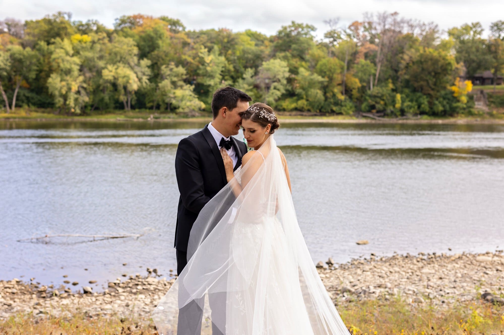 Bride and groom stand close together for an intimate portait at the Mississippi riverside in Leopold's Mississippi Gardens, NE Minneapolis