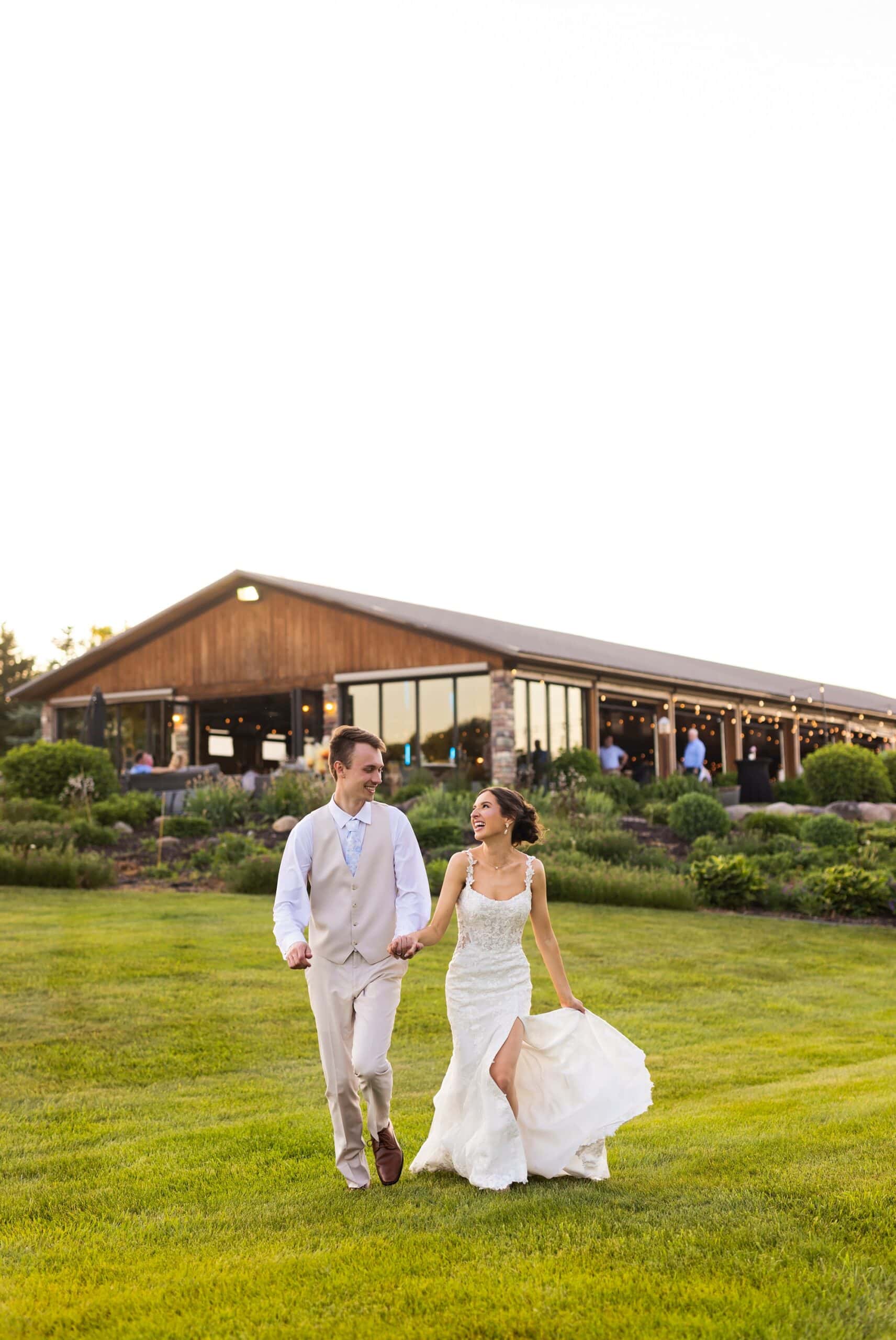 Newlyweds strolling hand in hand outside Ridgetop Events during wedding photography in Prescott, Wisconsin.