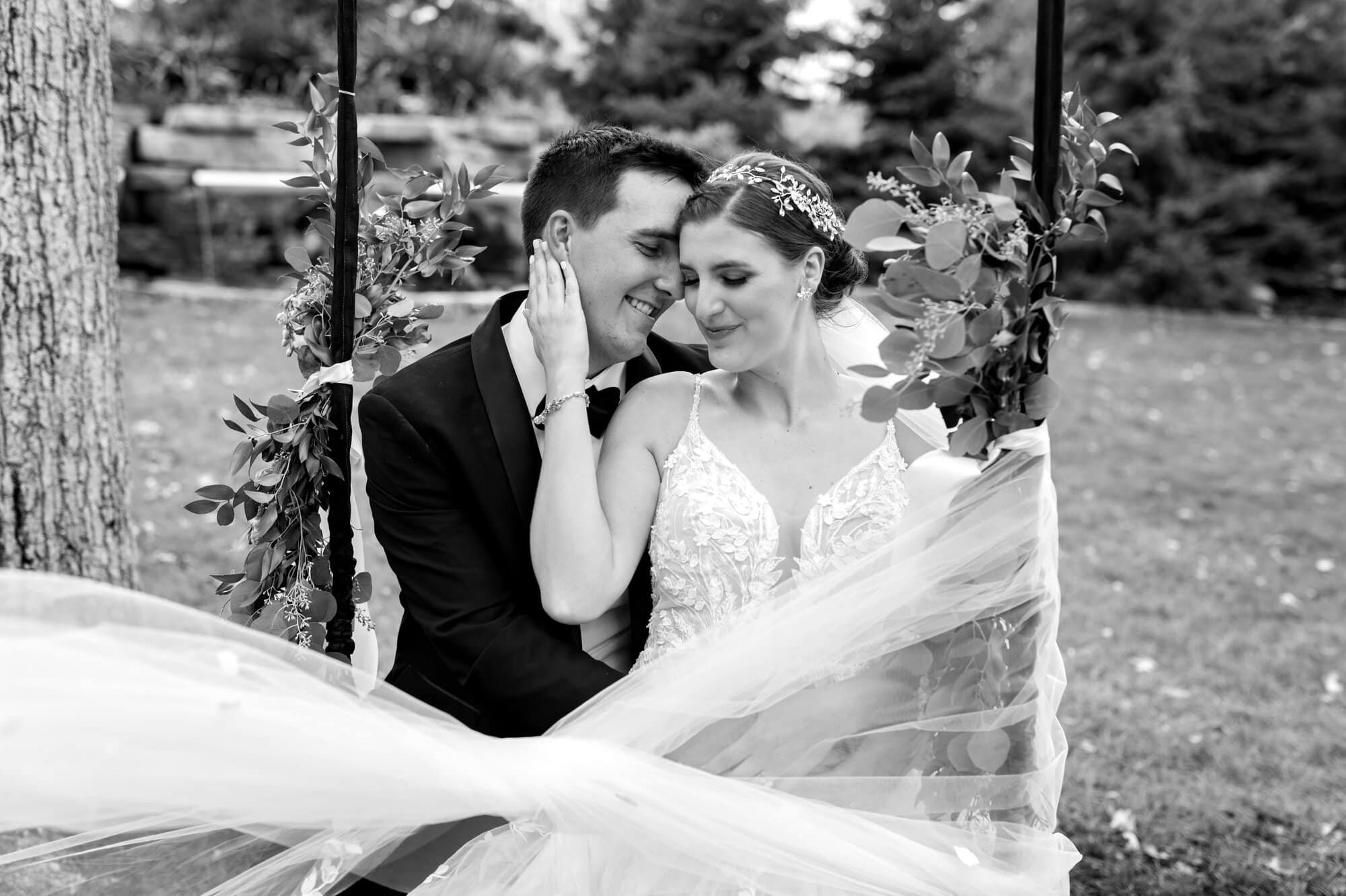 Bride and groom embracing on a decorated swing for black and white portaits in Leopold's Mississippi Gardens, NE Minneapolis