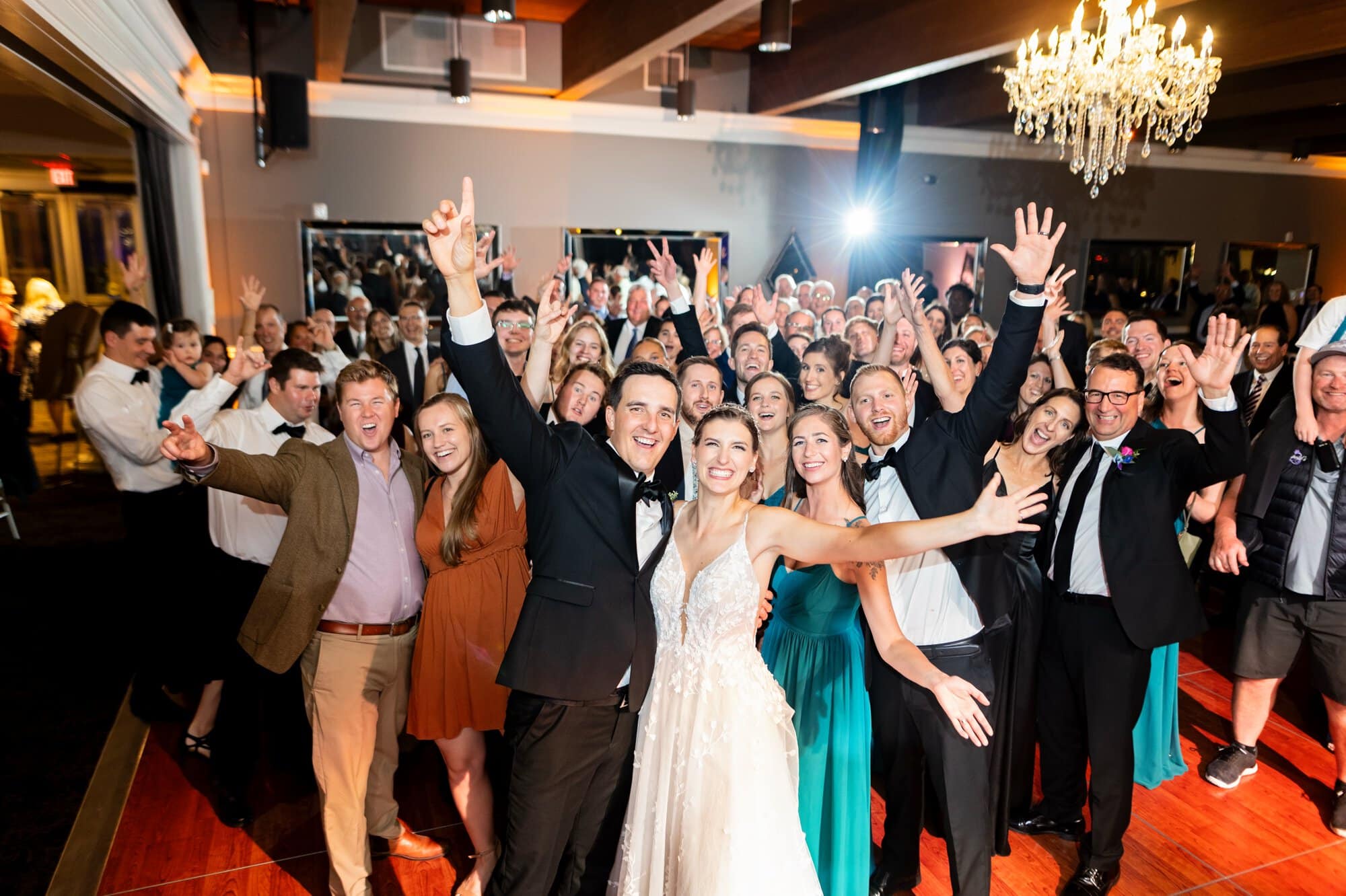 Wedding guests pose for a group photo with the bride and groom as they all celebrate joyously at the reception at Leopold's Mississippi Gardens, NE Minneapolis