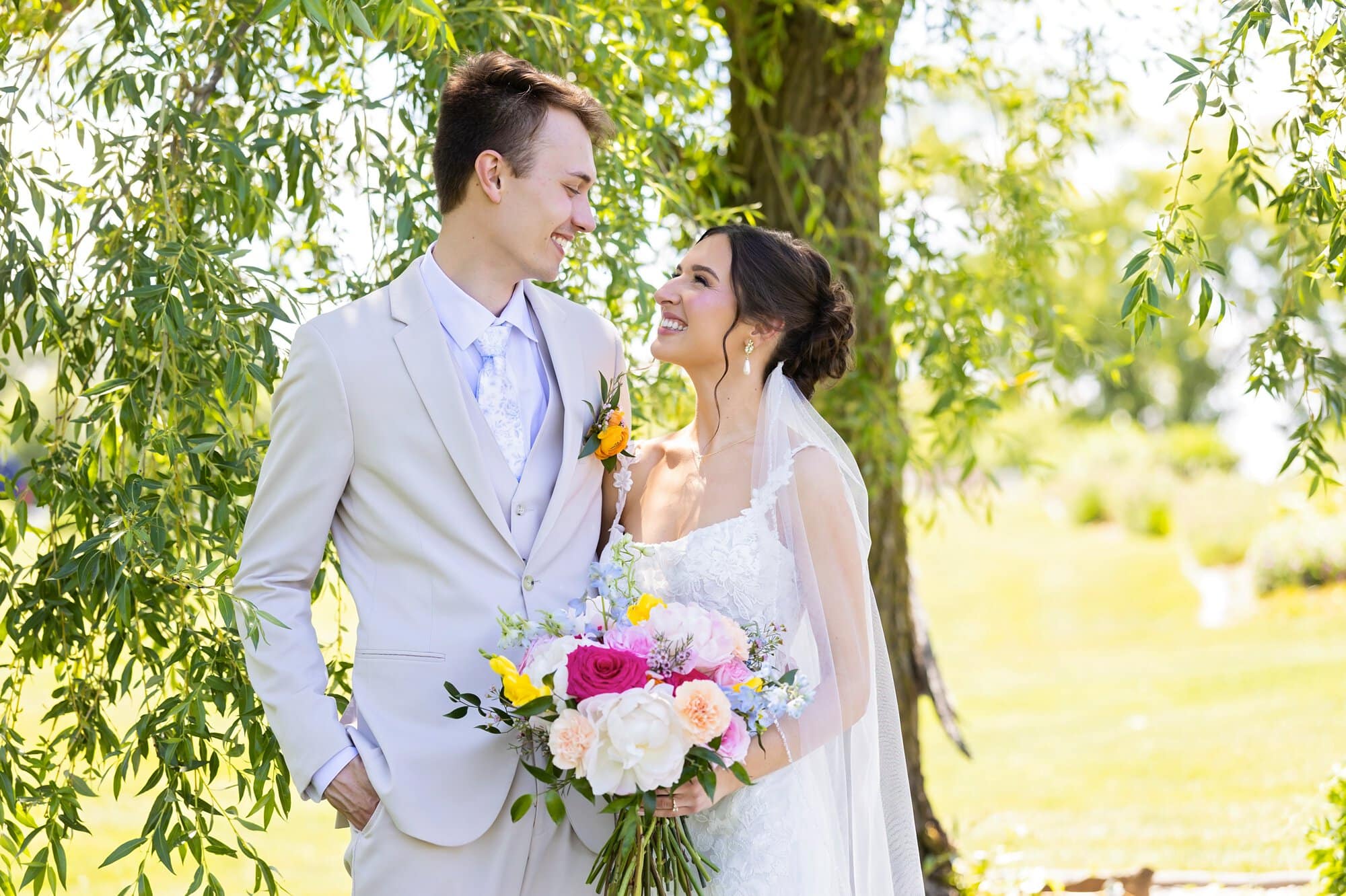 Bride and groom pose for a photo, smiling at each other during their wedding photography at Ridgetop Events.