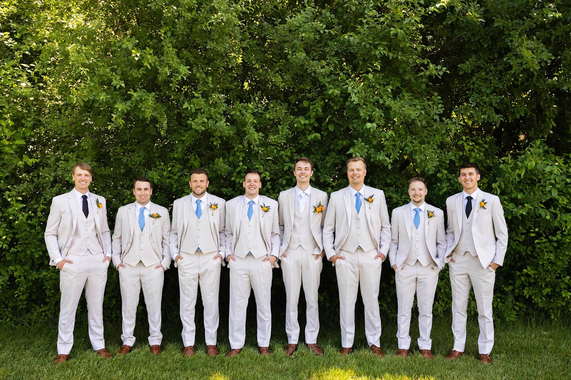 Groomsmen group photos with the groom. All standing in a row with their hands in their pockets outdoors at Ridgetop Events.
