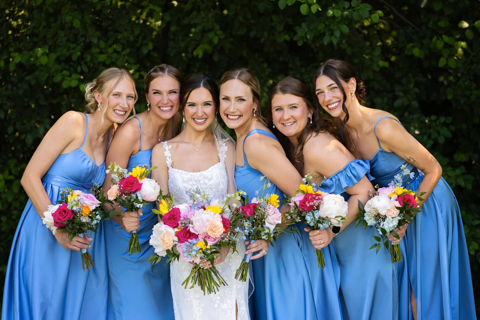 Bridesmaid group photos with the bride. All showing their bouquets and grouped around the bride elegantly at Ridgetop Events.