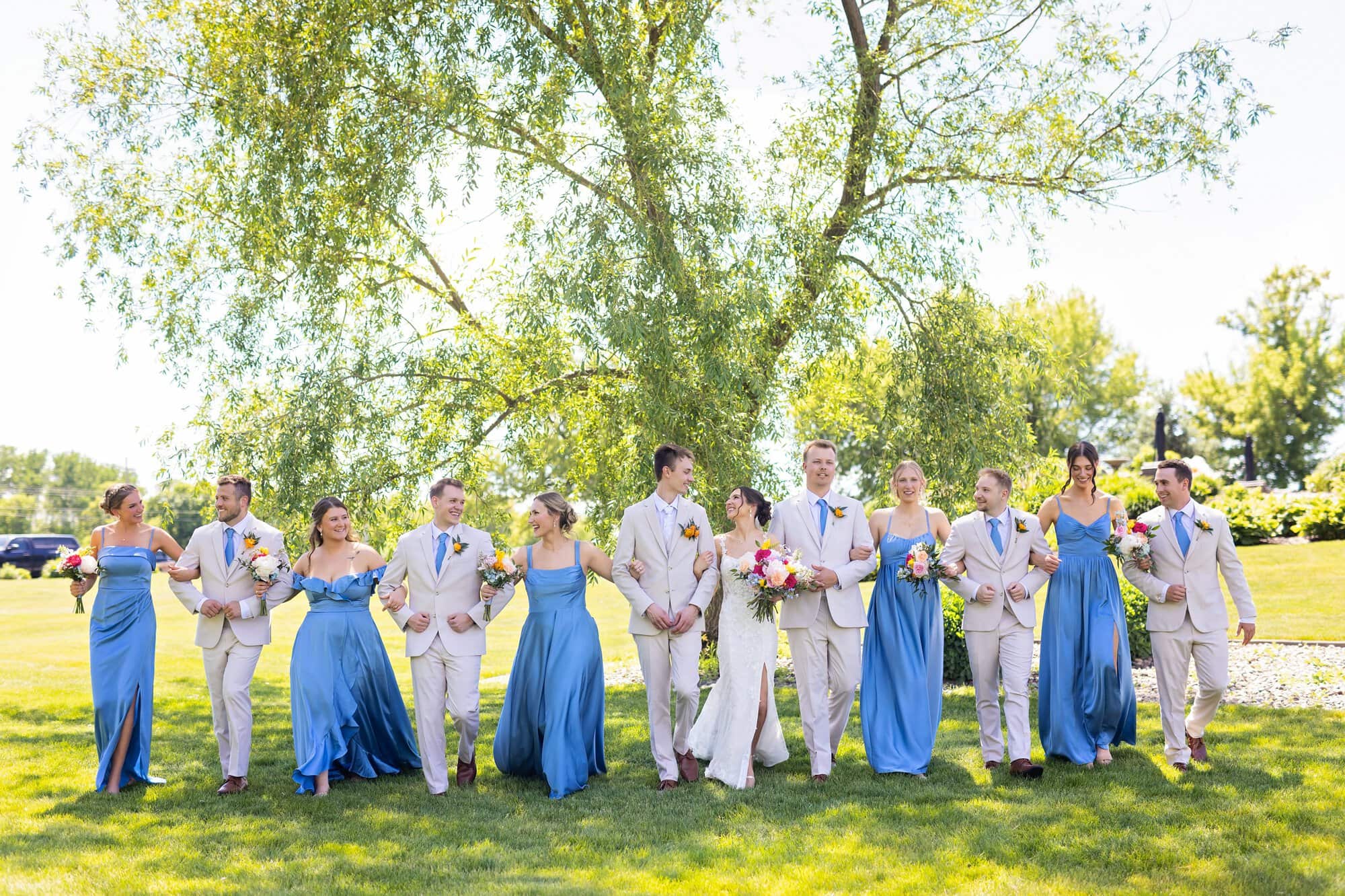 Bridal party walking with linked arms for wedding photography at Ridgetop Events in Prescott, WI.