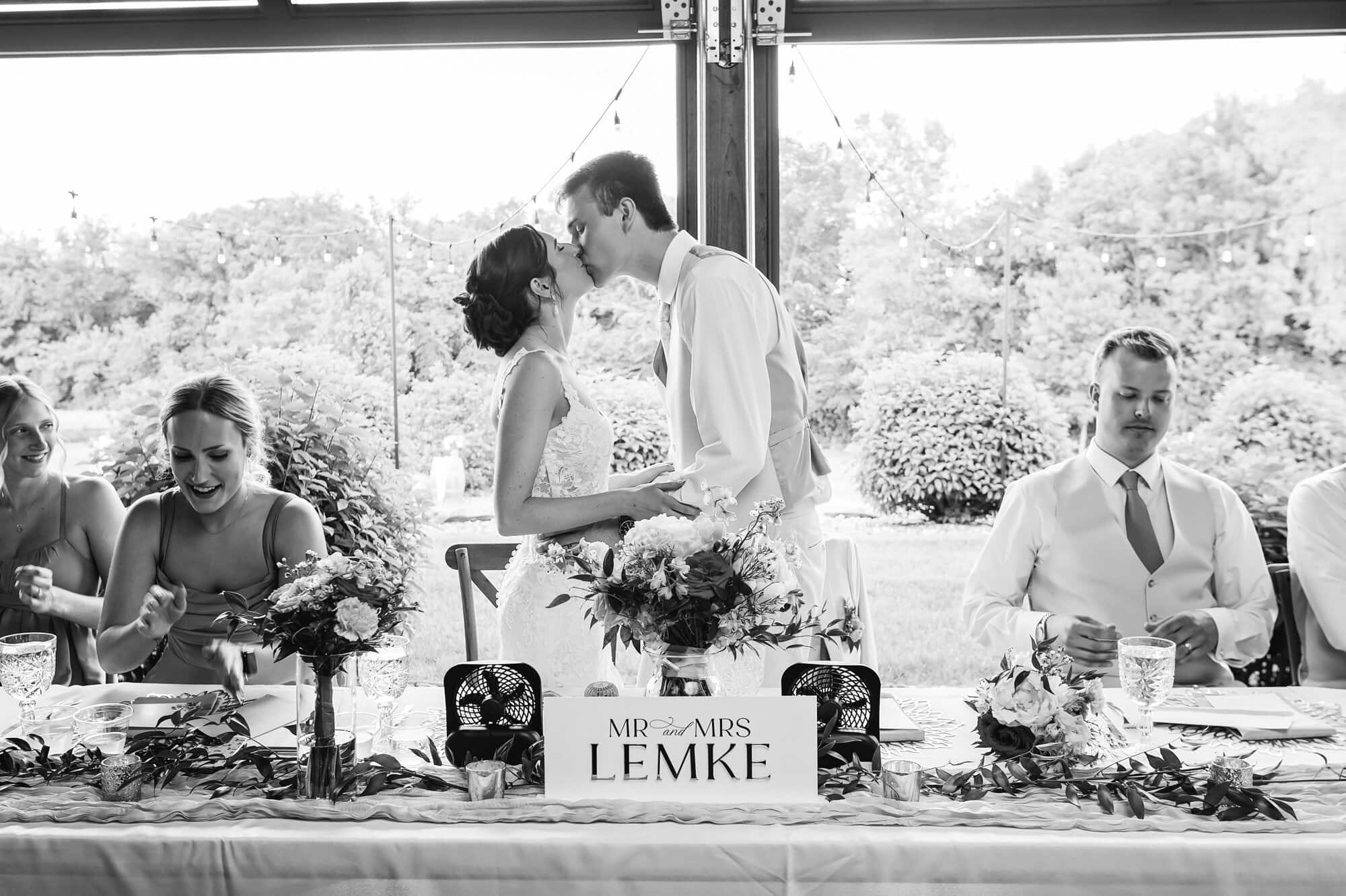 Bride and groom kiss at the head table at Ridgetop Events in Prescott, WI.