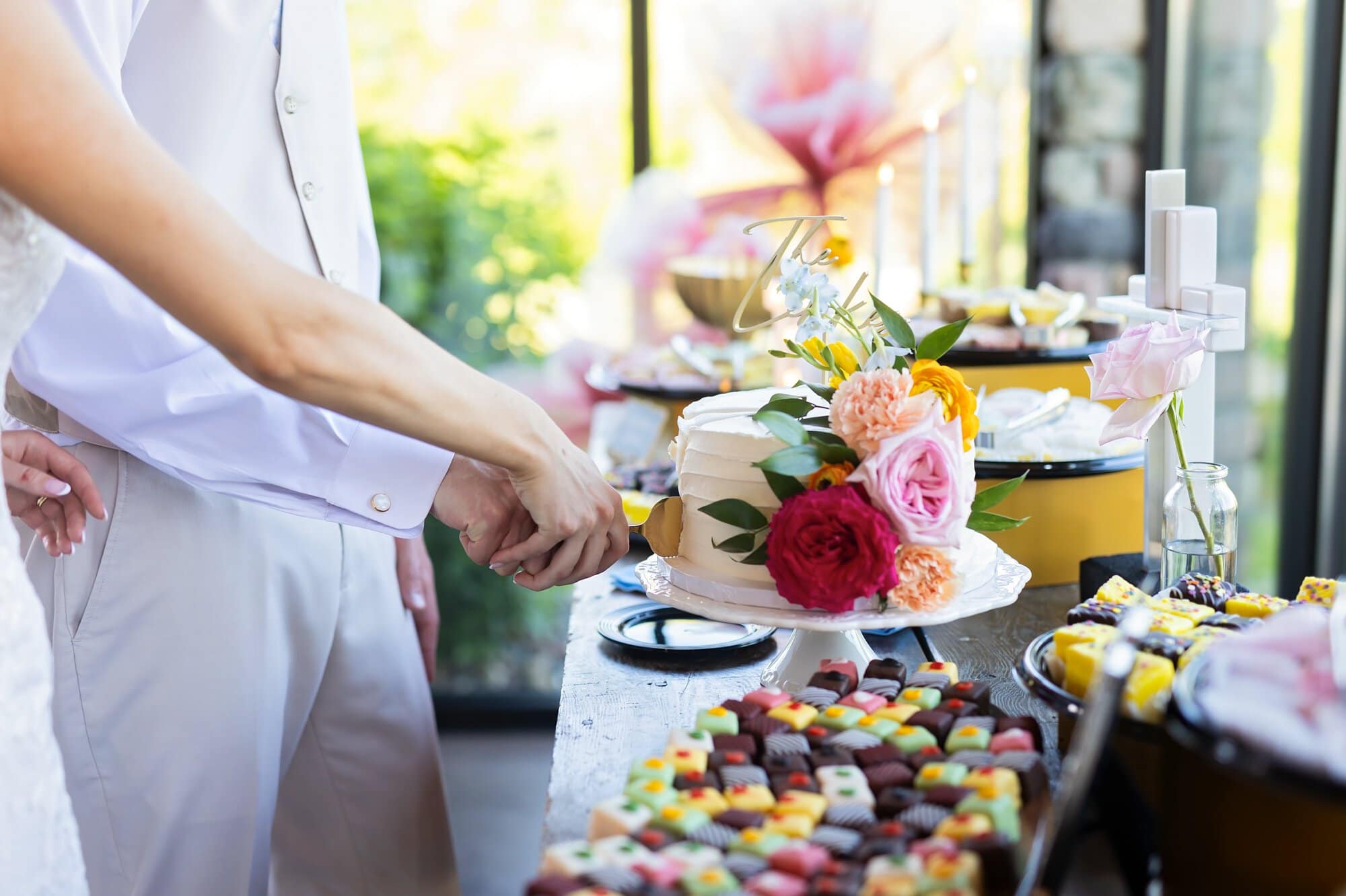 Couple cuts the wedding cake at the dessert table.
