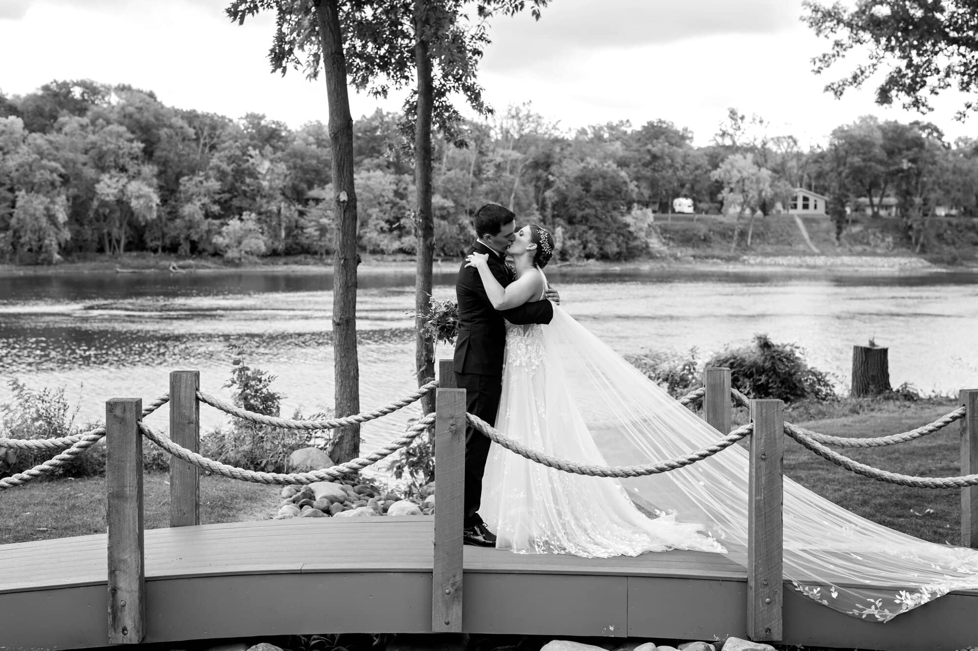 Bride and groom kissing on a bridge for black and white portraits at the Mississippi riverside in Leopold's Mississippi Gardens, NE Minneapolis