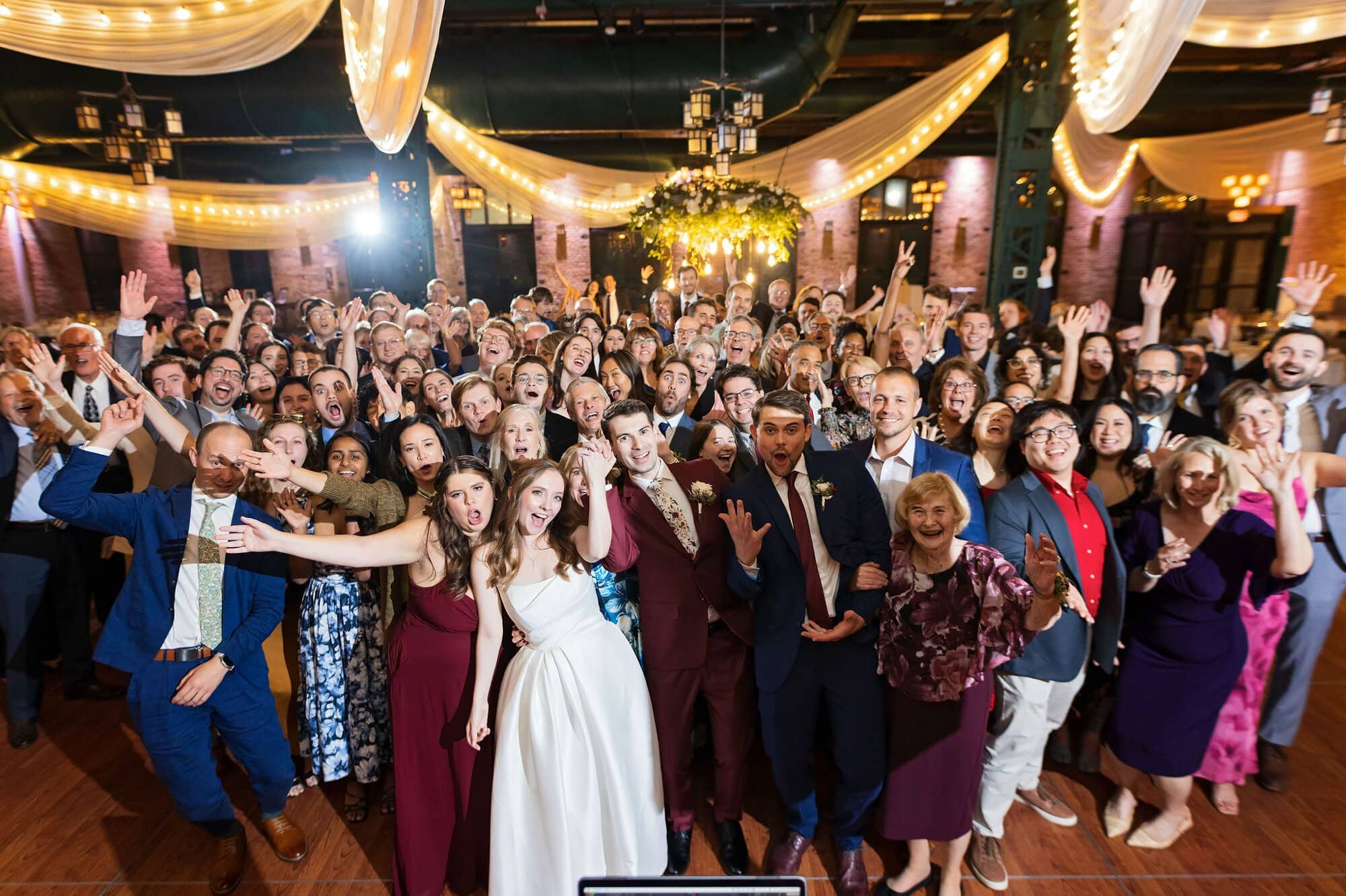 Guests pose for a group photo at a wedding reception at Nicollet Island Pavilion in Minneapolis Minnesota
