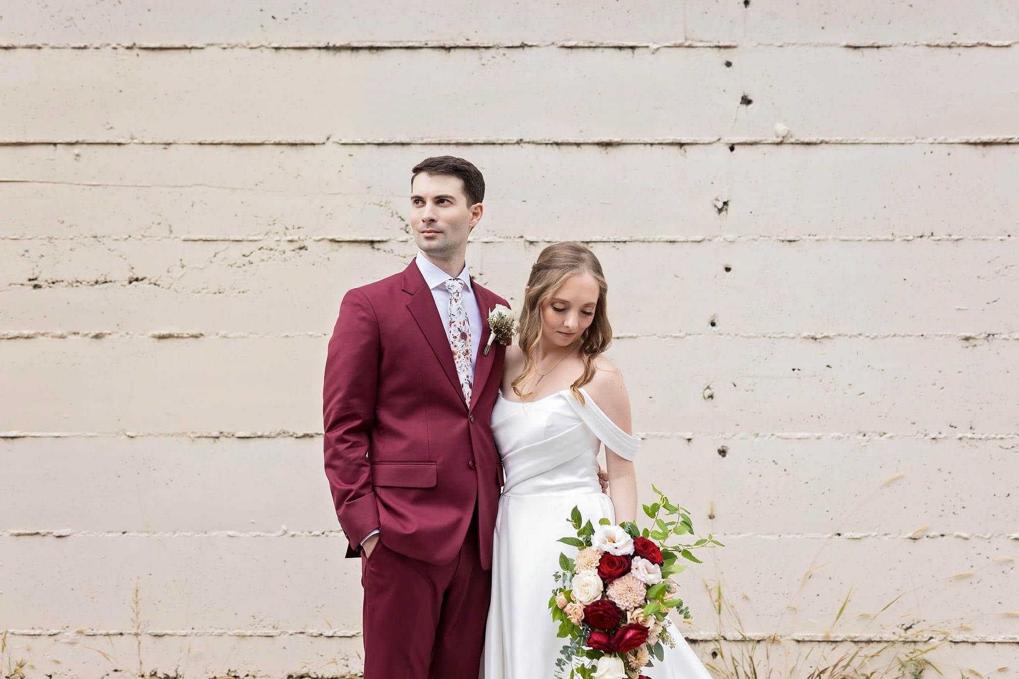 Bride and groom pose for couple wedding photos in front of distressed exterior walls along Saint Anthony Main in Minneapolis Minnesota