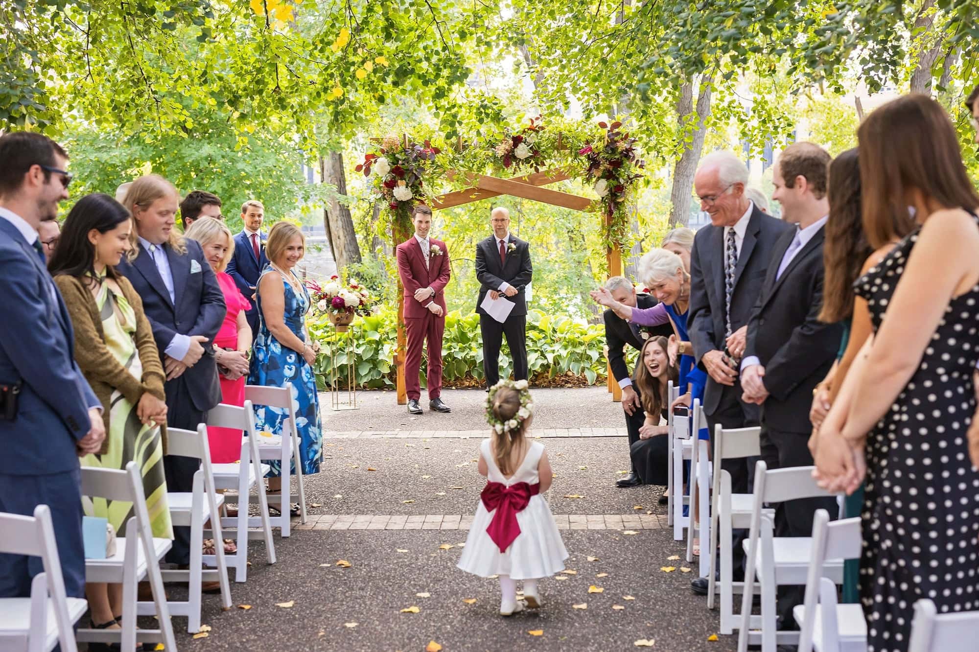 A flower girl walks down the aisle at a wedding on the Nicollet Island Pavilion patio in Minneapolis Minnesota