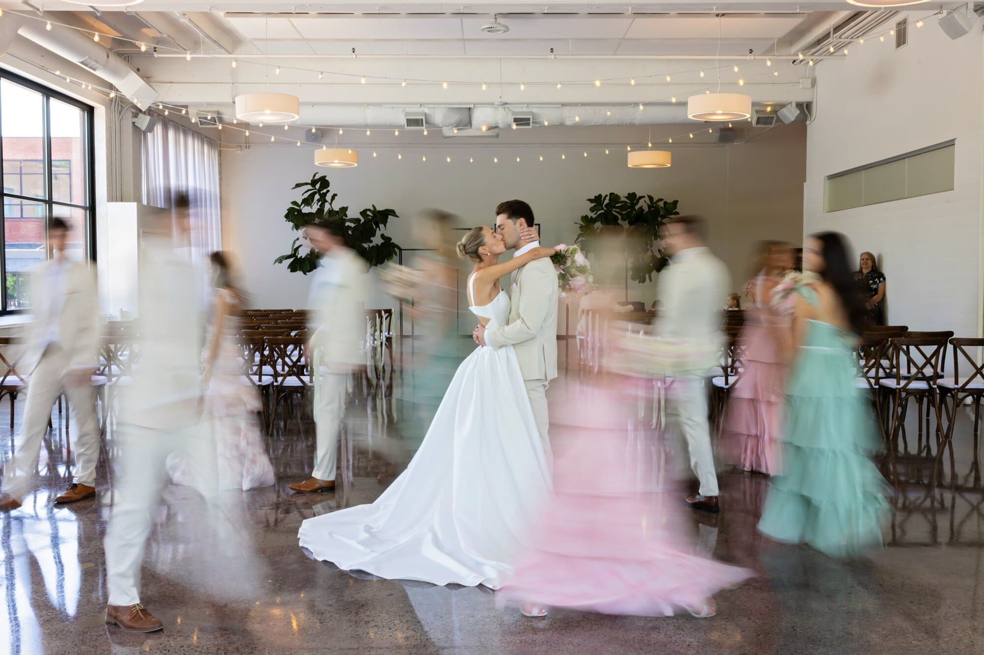 The wedding party moves around the stationery bride and groom creating a photo in motion for pre-ceremony photos at the Urban Daisy in Minneapolis, Minnesota